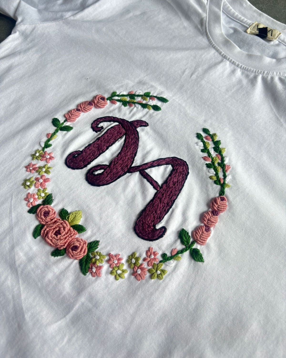 White t-shirt with embroidered letter 'D' surrounded by flowers