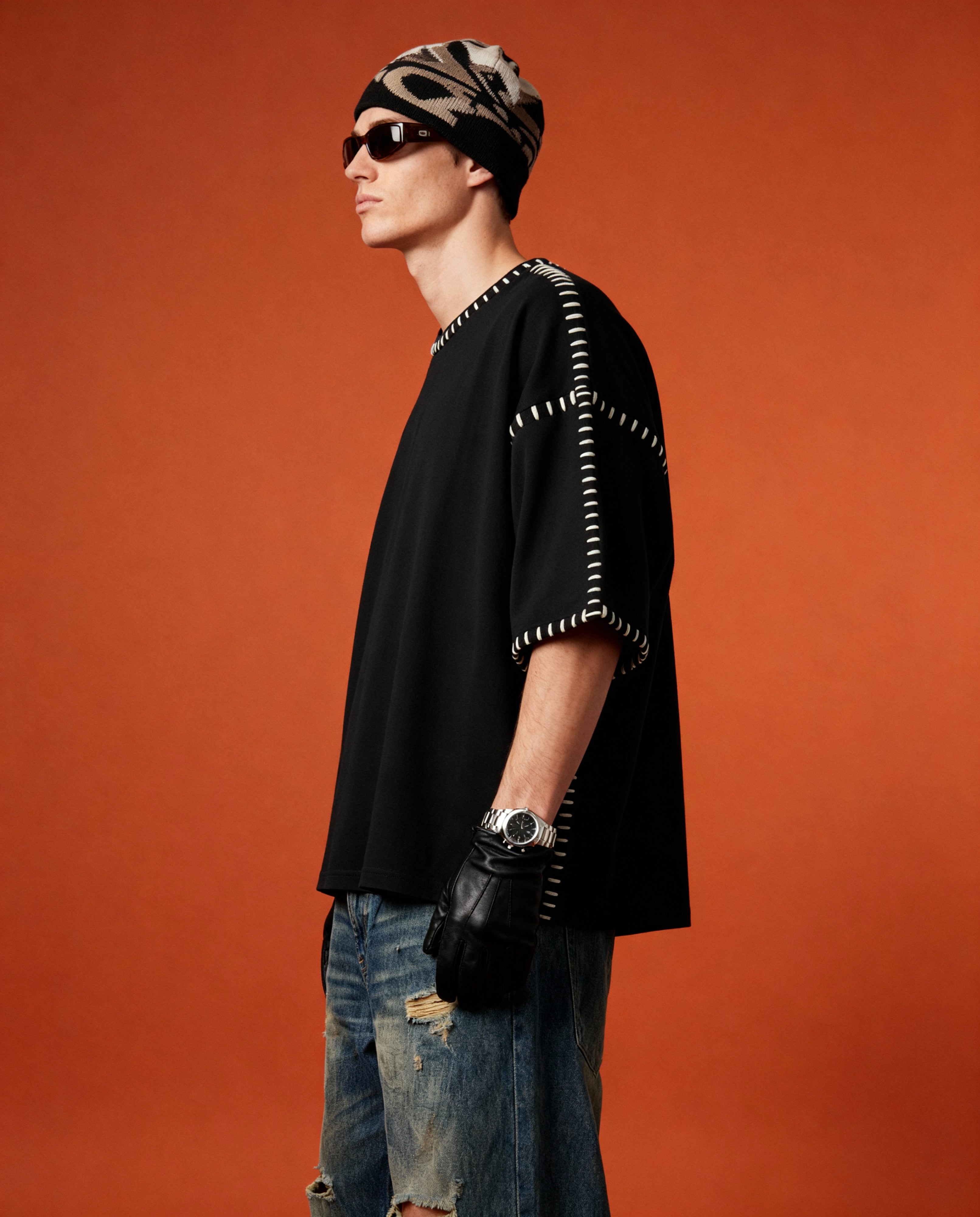 Person wearing a black outfit with white patterns against an orange background