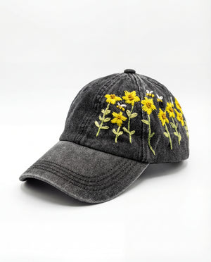 Black denim cap with yellow floral sunflower embroidery on a white background