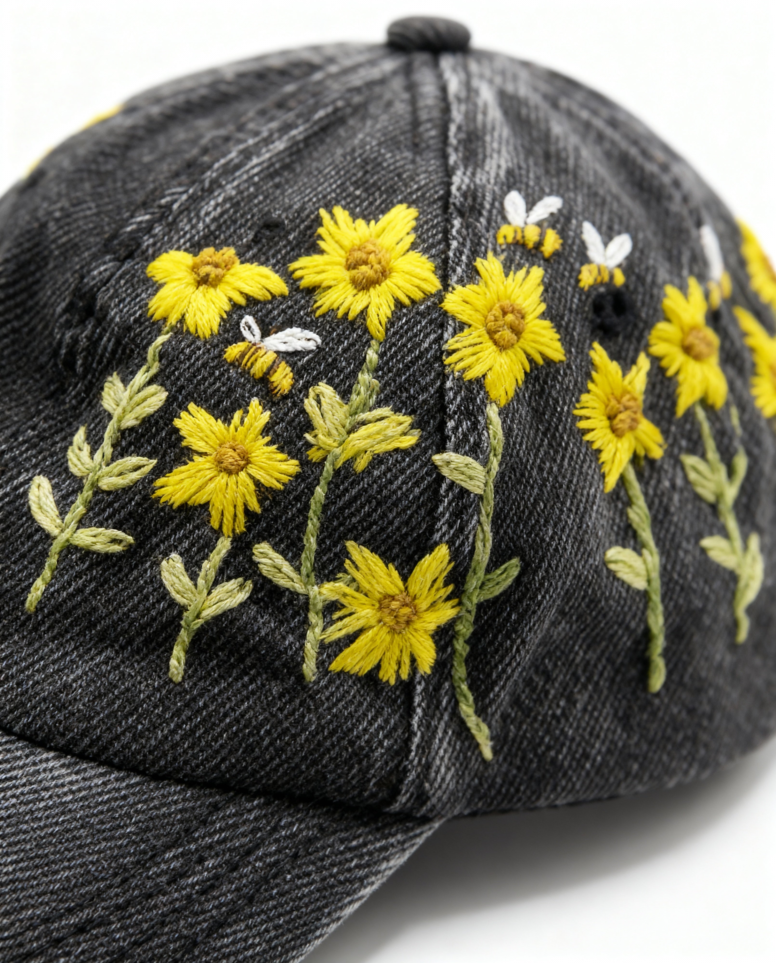 Black denim cap with yellow floral embroidery on a white background