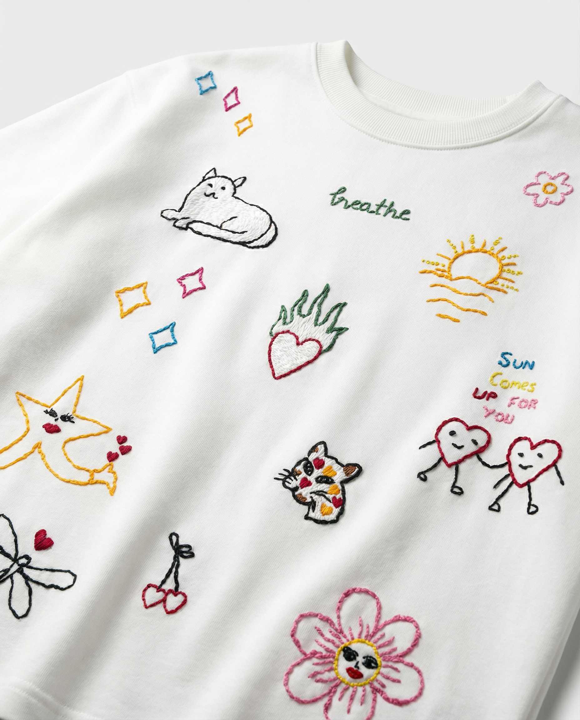 White T-shirt with colorful embroidered designs on a light gray background