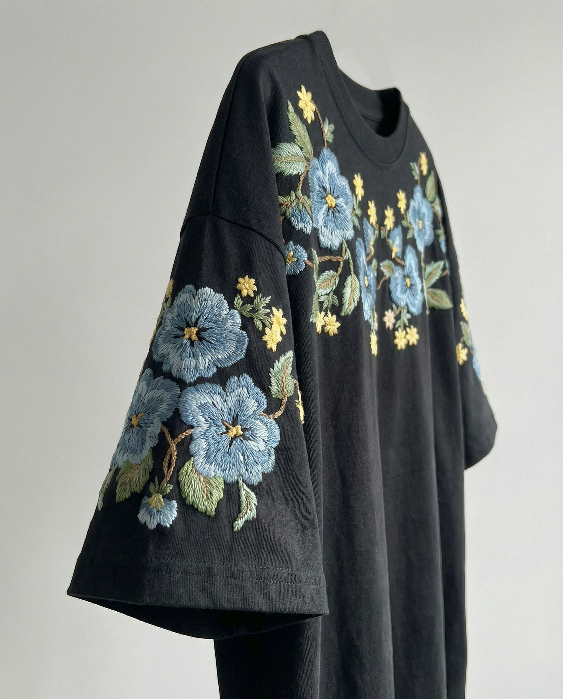 side view of Black t-shirt with floral embroidery on a gray background