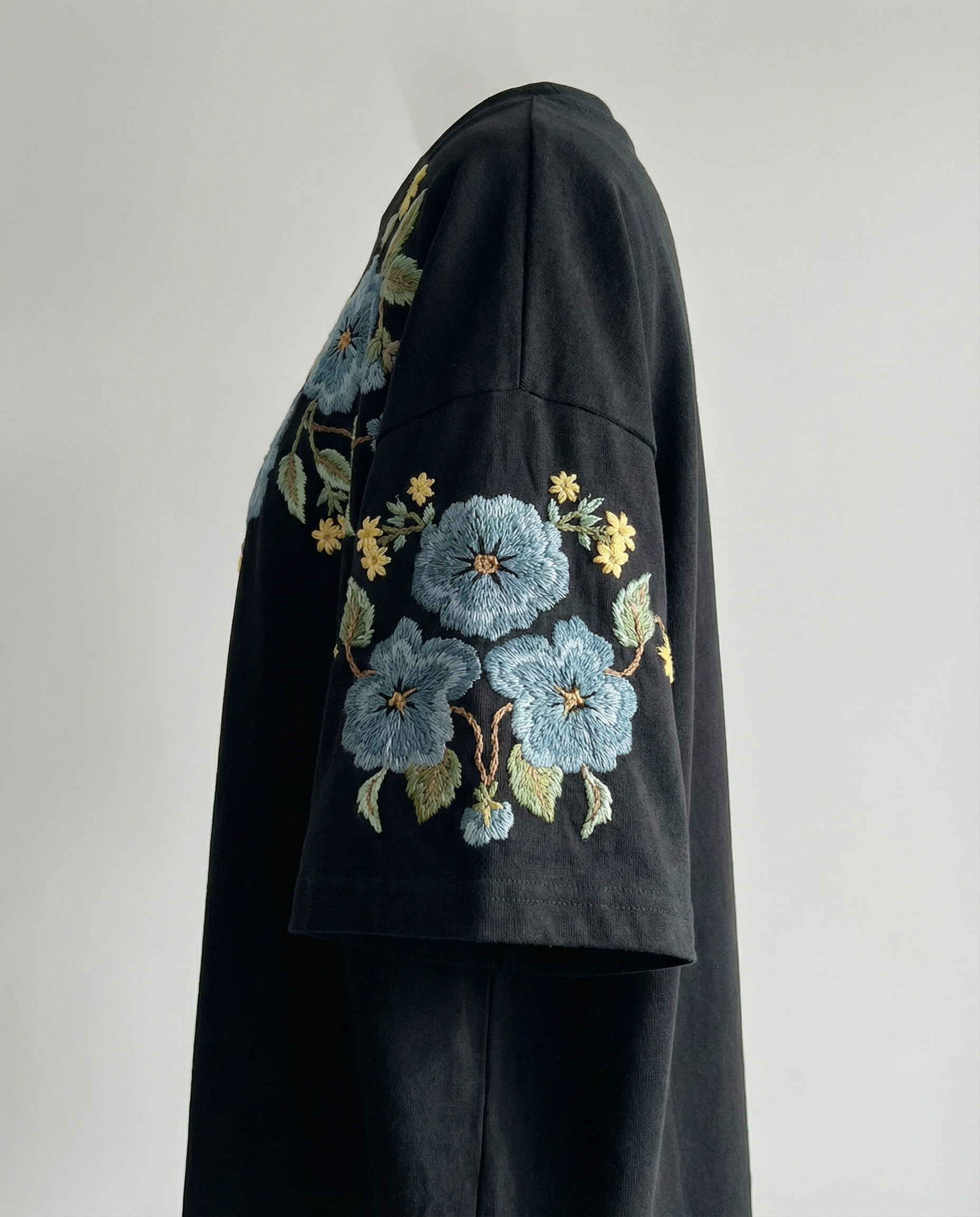 Black garment with floral embroidery on a plain background