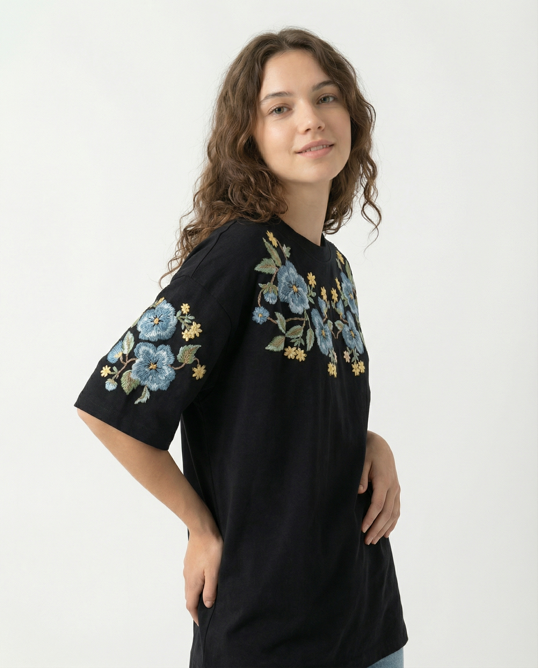Woman wearing a black t-shirt with floral hand embroidery on a white background