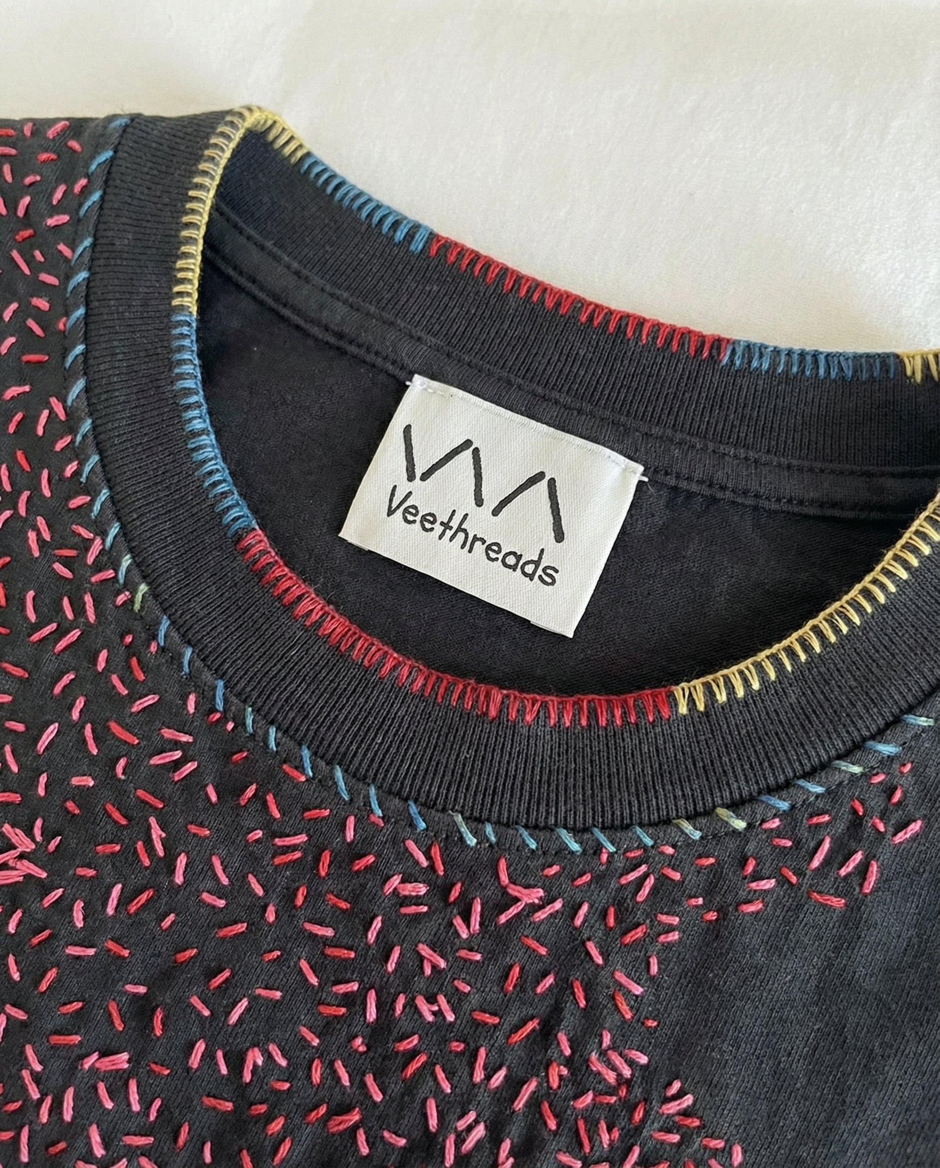 Close-up of a garment with embroidered stitching and Veethreads label.