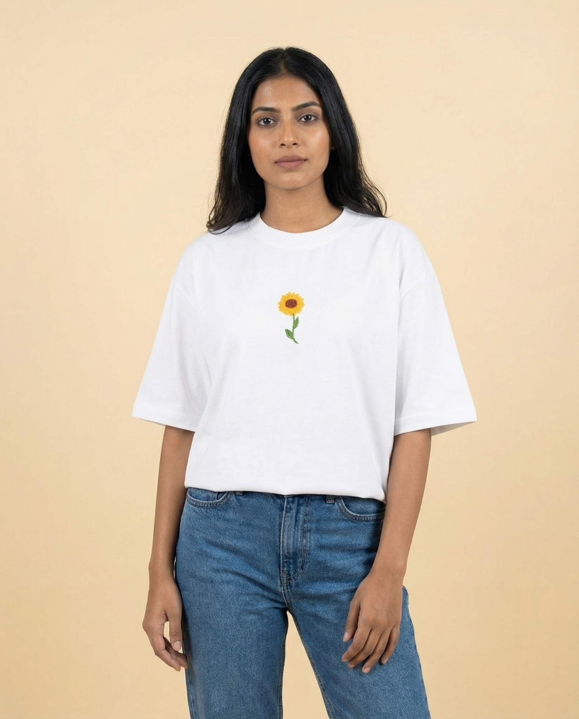 Person wearing a white t-shirt with a sunflower design on a beige background