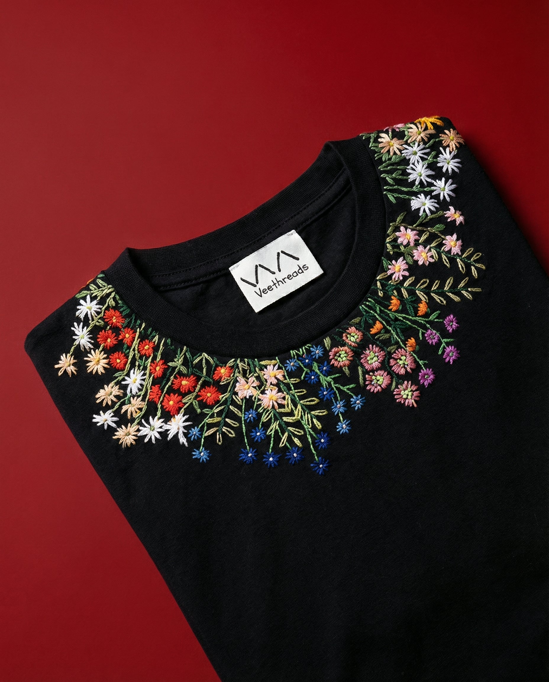 Black top with colorful floral embroidery on a red background