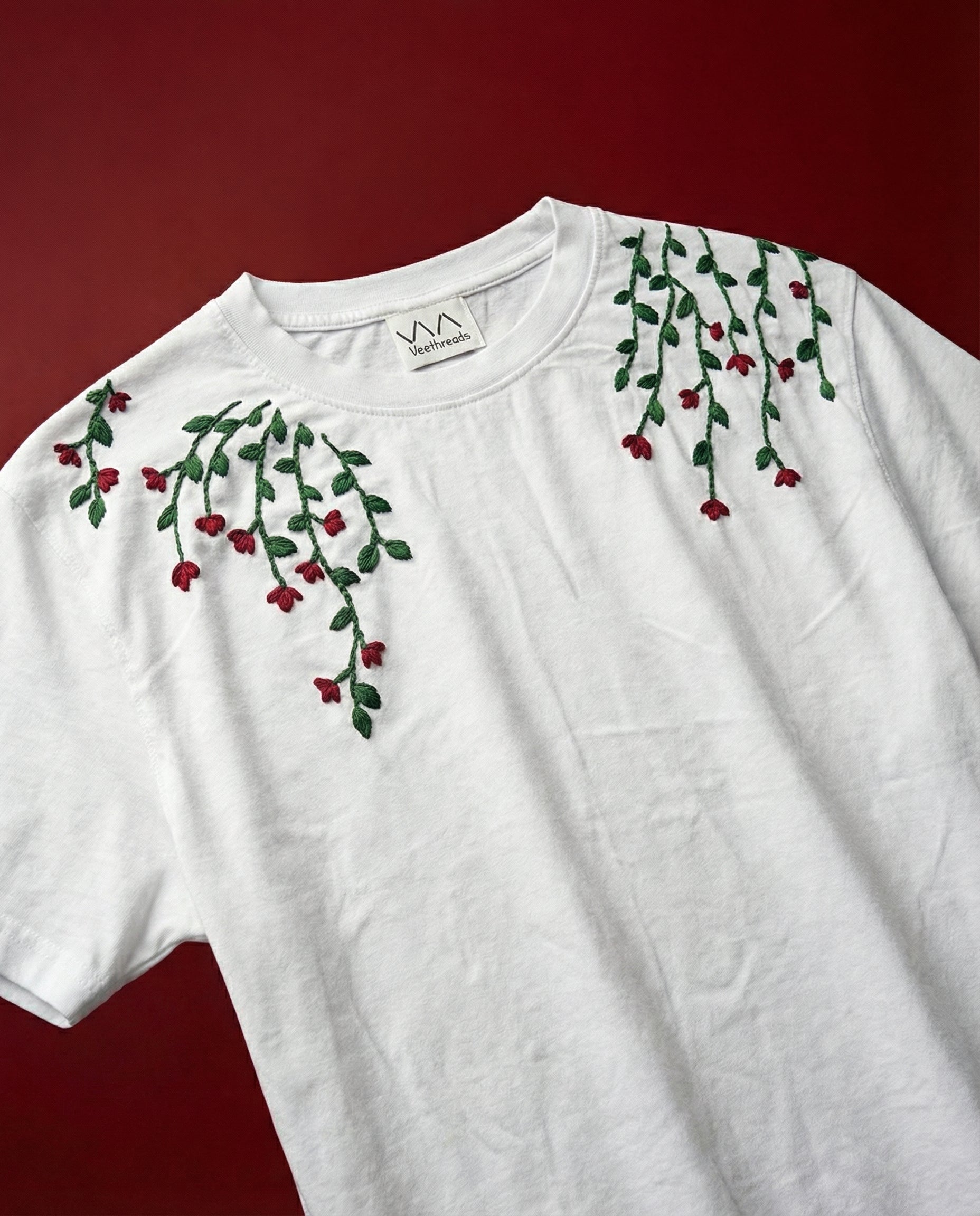 White t-shirt with floral vines embroidery on a red background