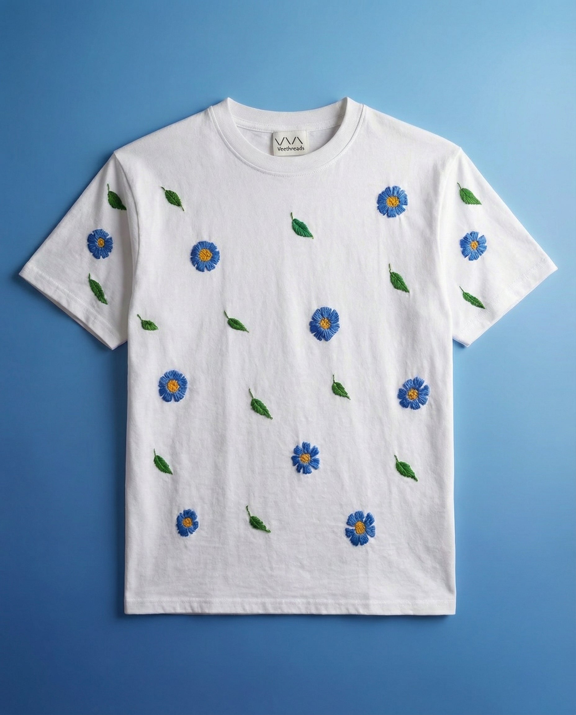 Hand embroidered floral tshirt blue — white cotton tee with hand-stitched blue floral patterns on blue background, azure bloom design