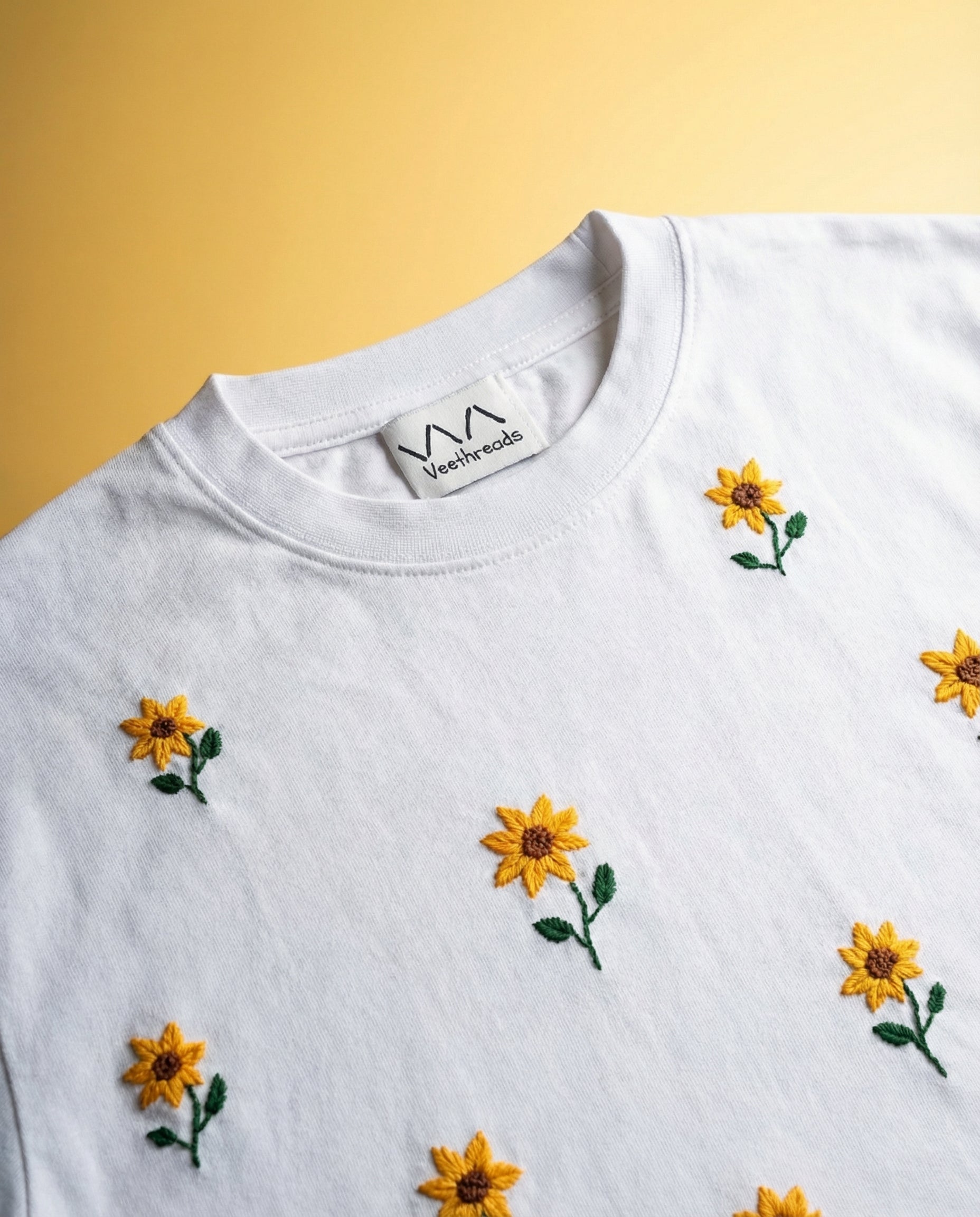 White sweatshirt with yellow floral embroidery on a yellow background