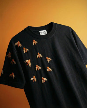 Black t-shirt with bee designs embroidered on an orange background