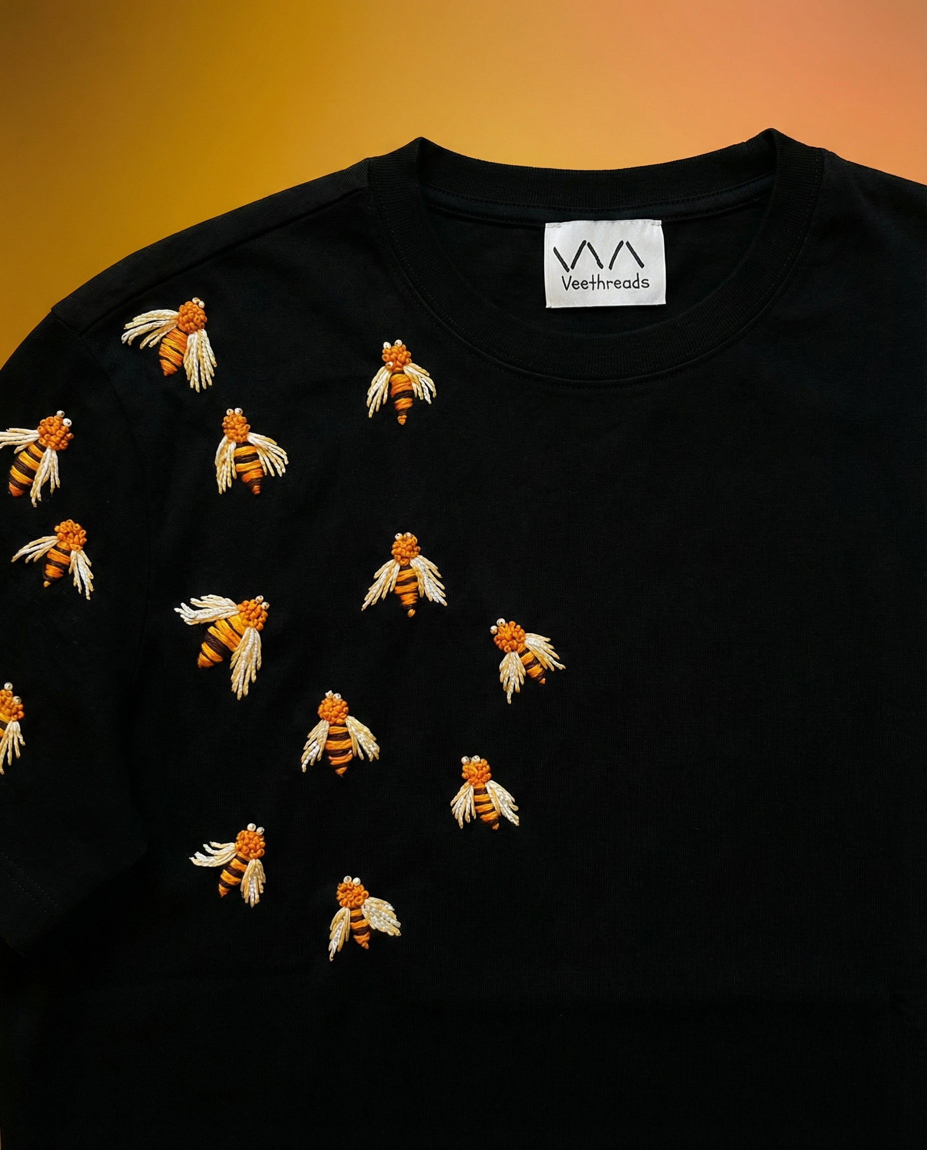Black shirt with embroidered bees on a gradient background