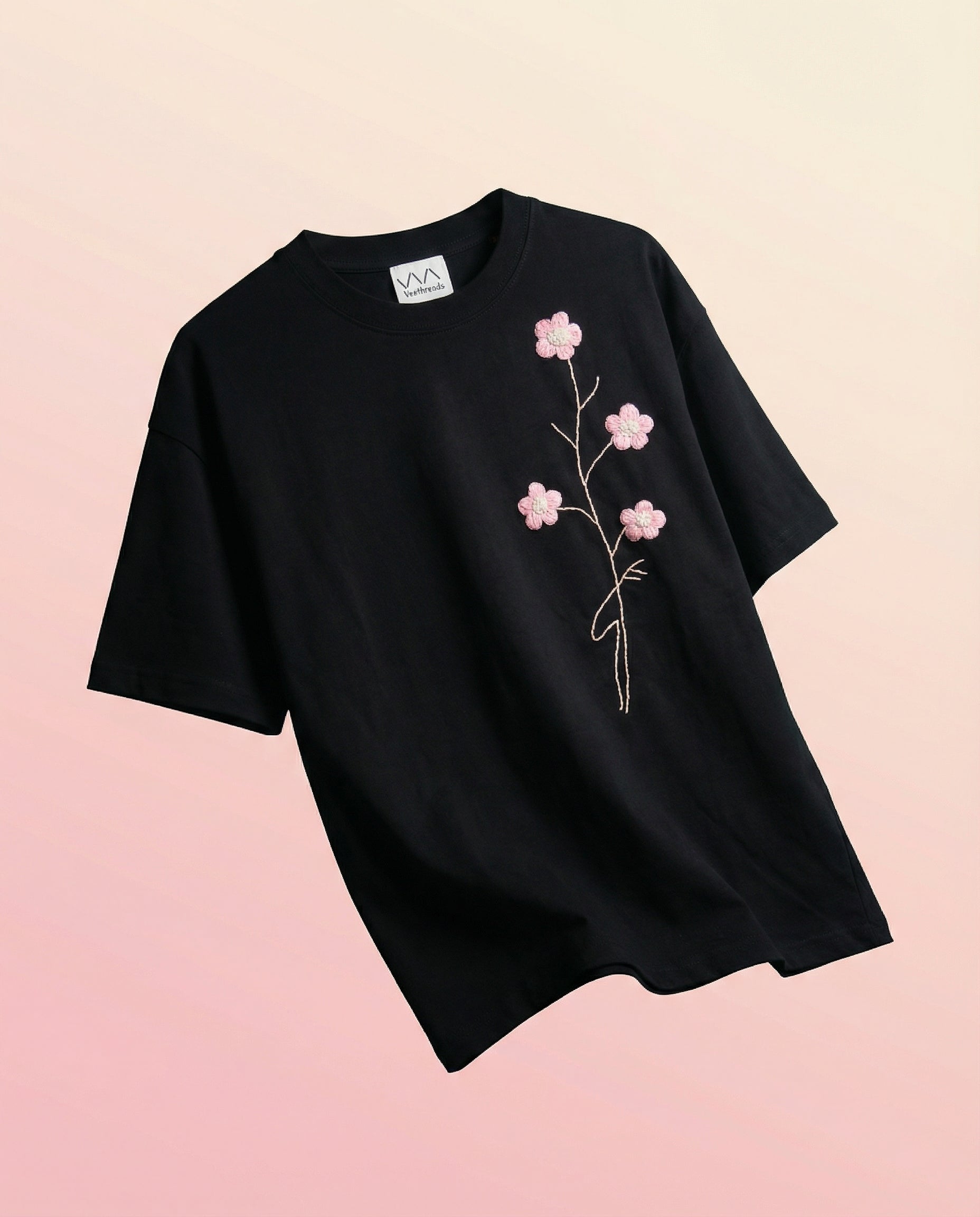 Black t-shirt with pink floral design on a beige background
