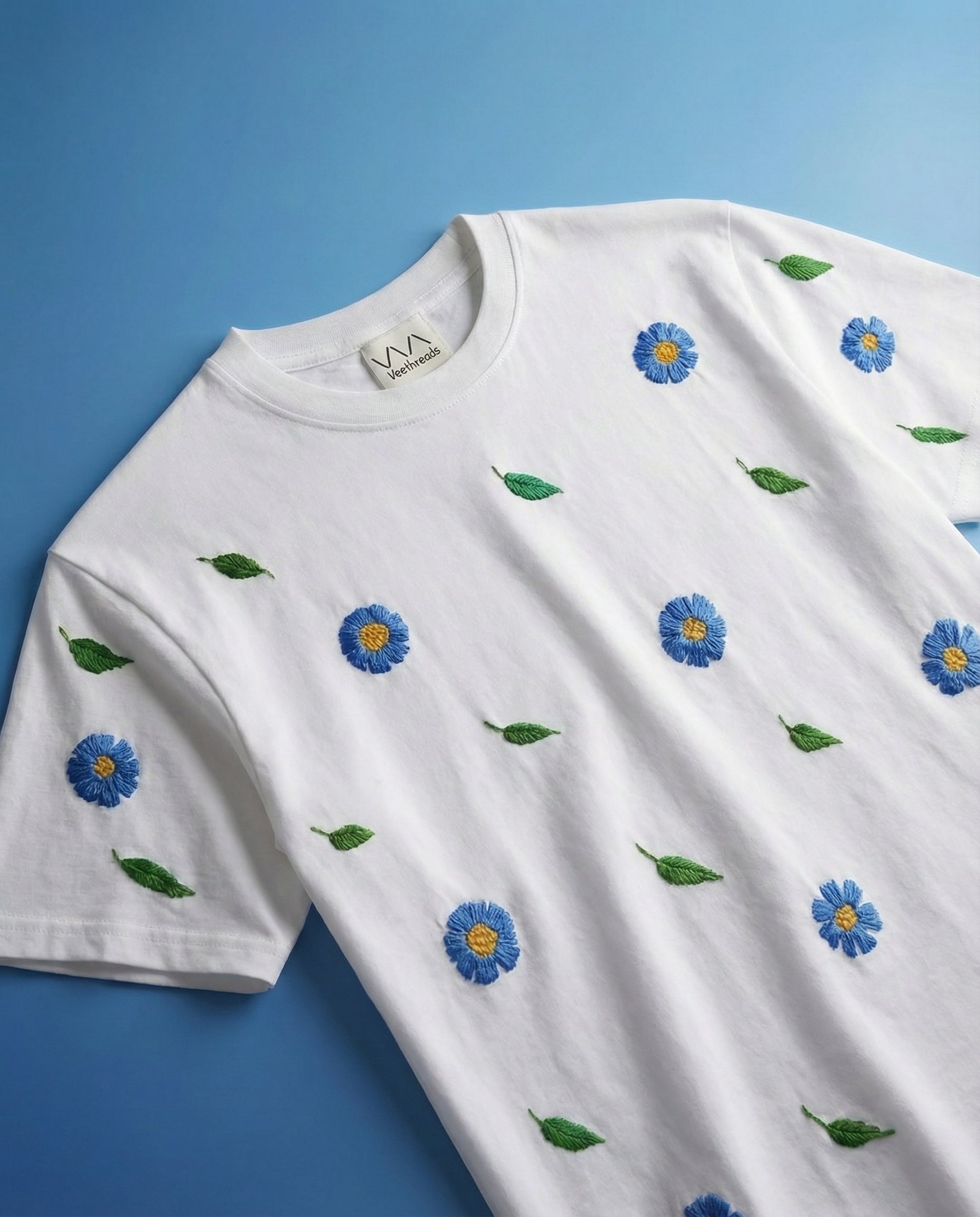 Blue floral embroidered tee — white cotton tee with hand-embroidered blue florals across the chest in real thread