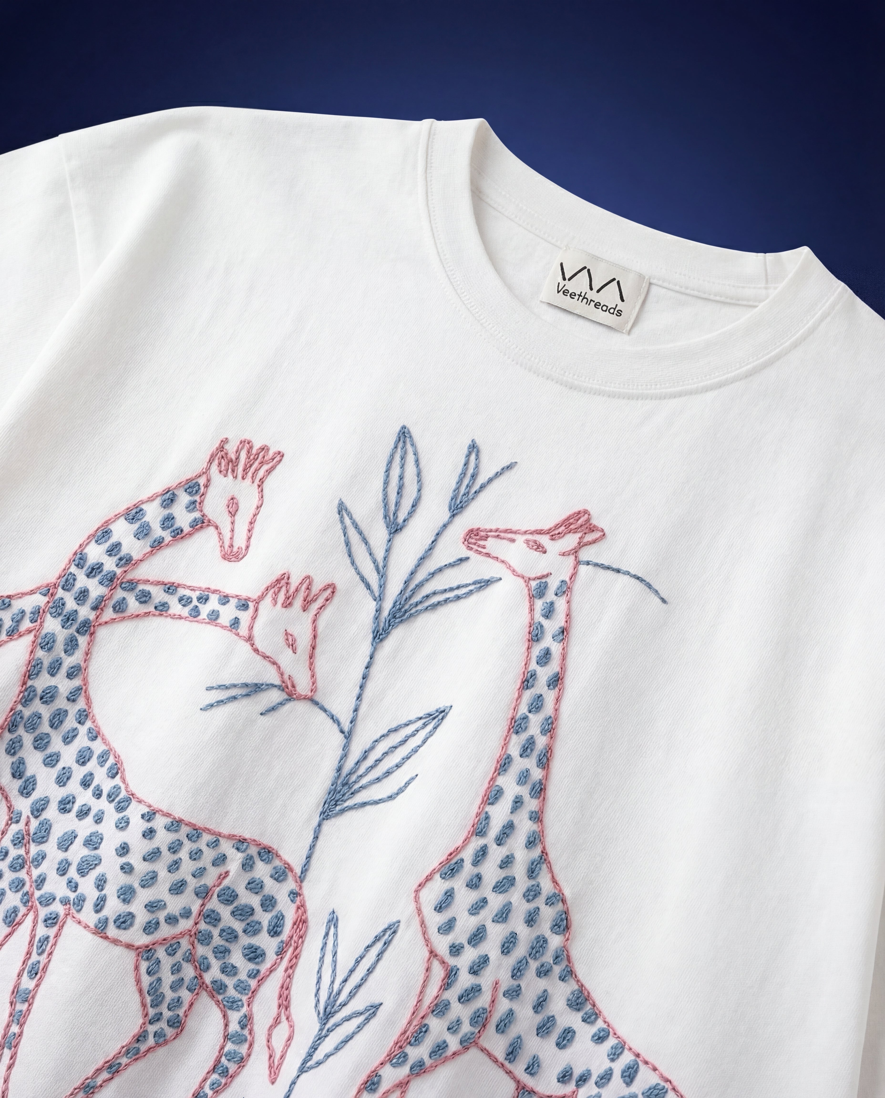close up giraffe embroidery with botanical leaves on white cotton t shirt