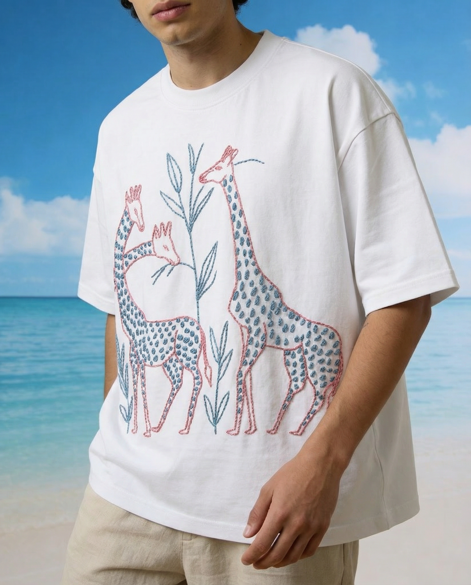 Person wearing a white t-shirt with giraffe design embroidery on a beach
