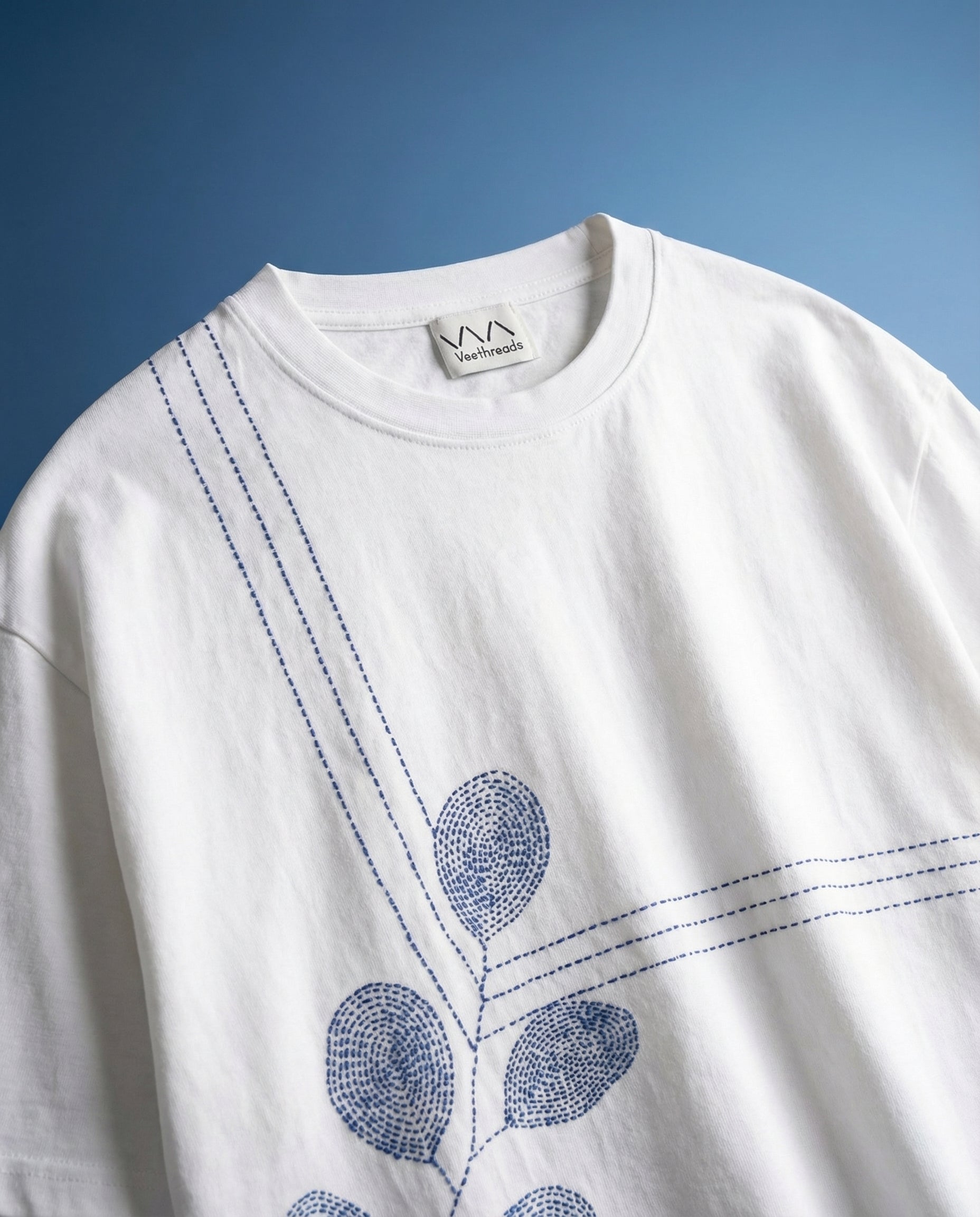 White sweatshirt with blue floral embroidery on a blue background