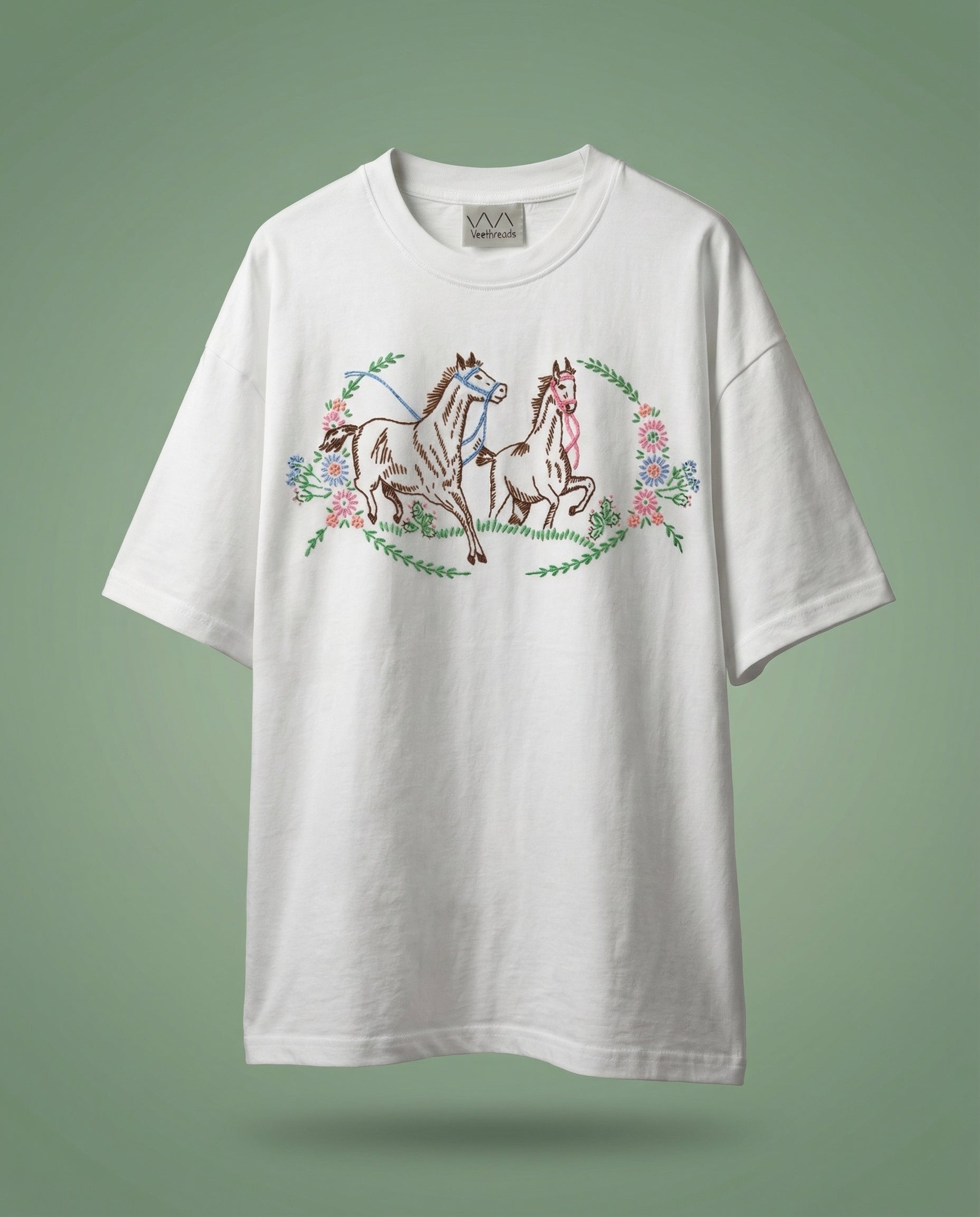 White t-shirt with horse and floral design on a green background