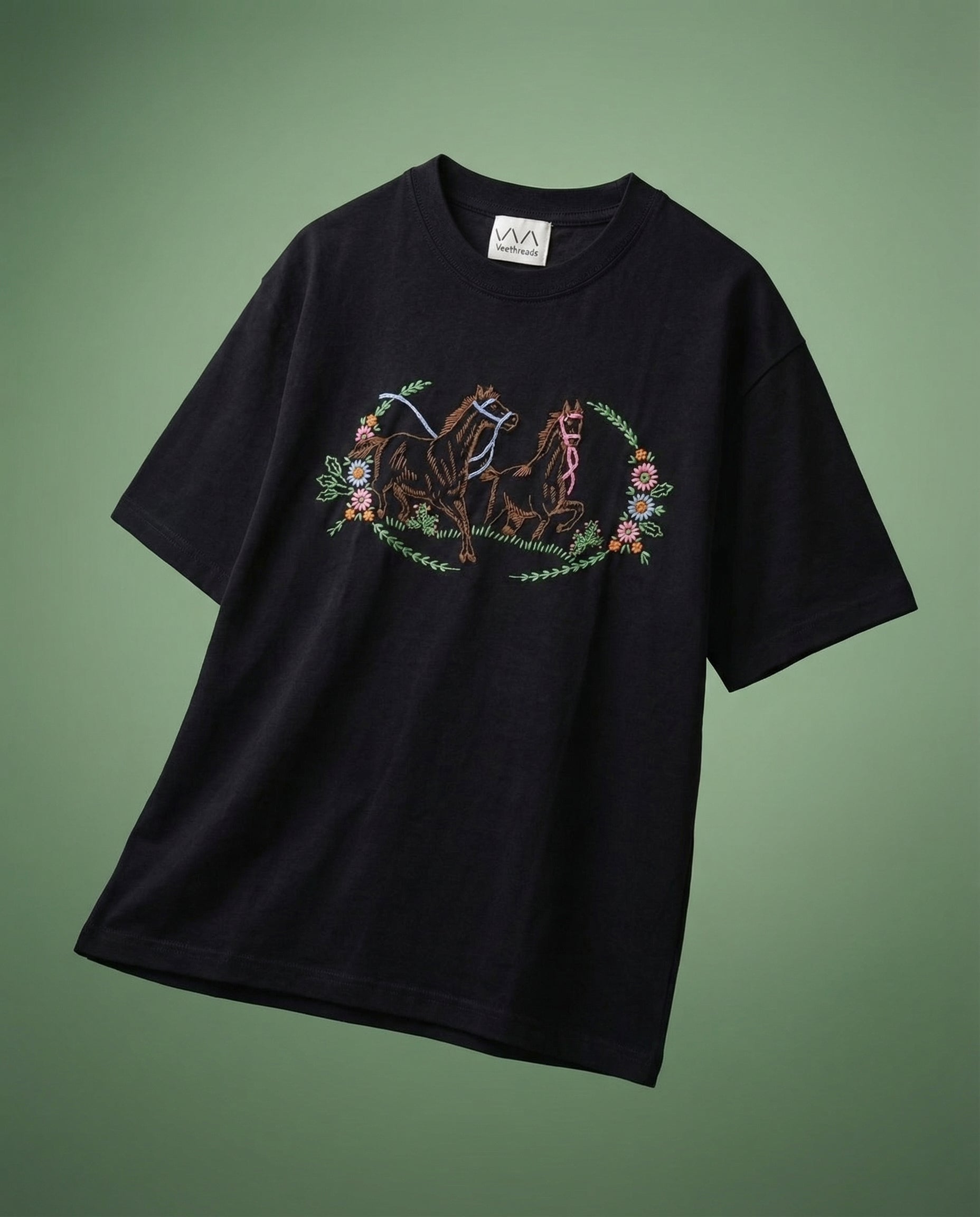 Wild prairie horse hand embroidered tee — black cotton tee with hand-embroidered horse and floral design on green background