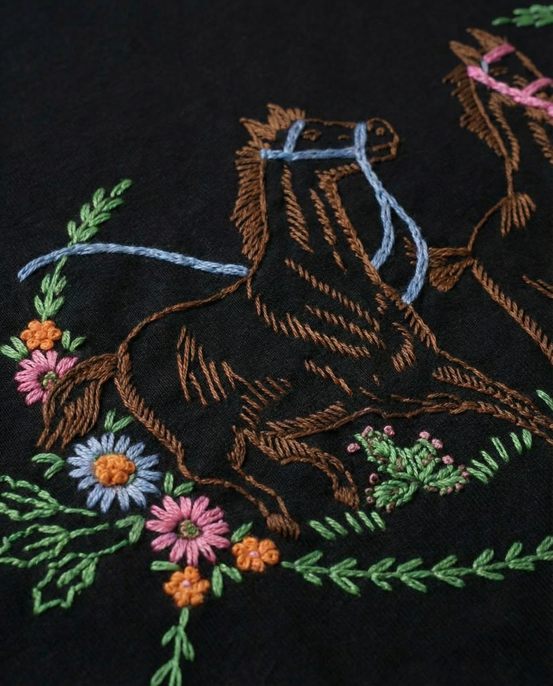 Embroidered design of a horse and floral elements on black fabric