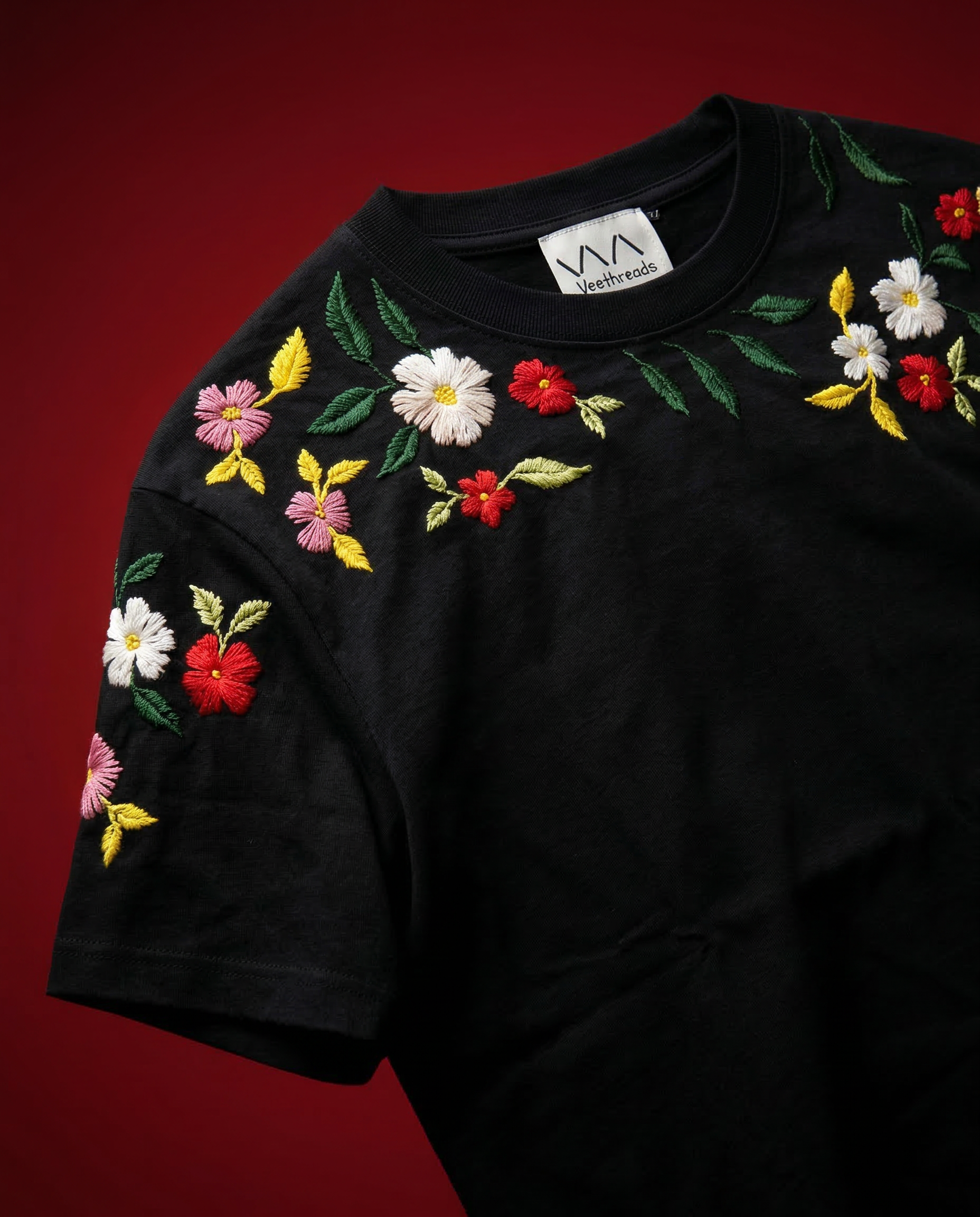 Close-up of hand embroidered red and white flowers on black Bloom Garland t-shirt sleeve