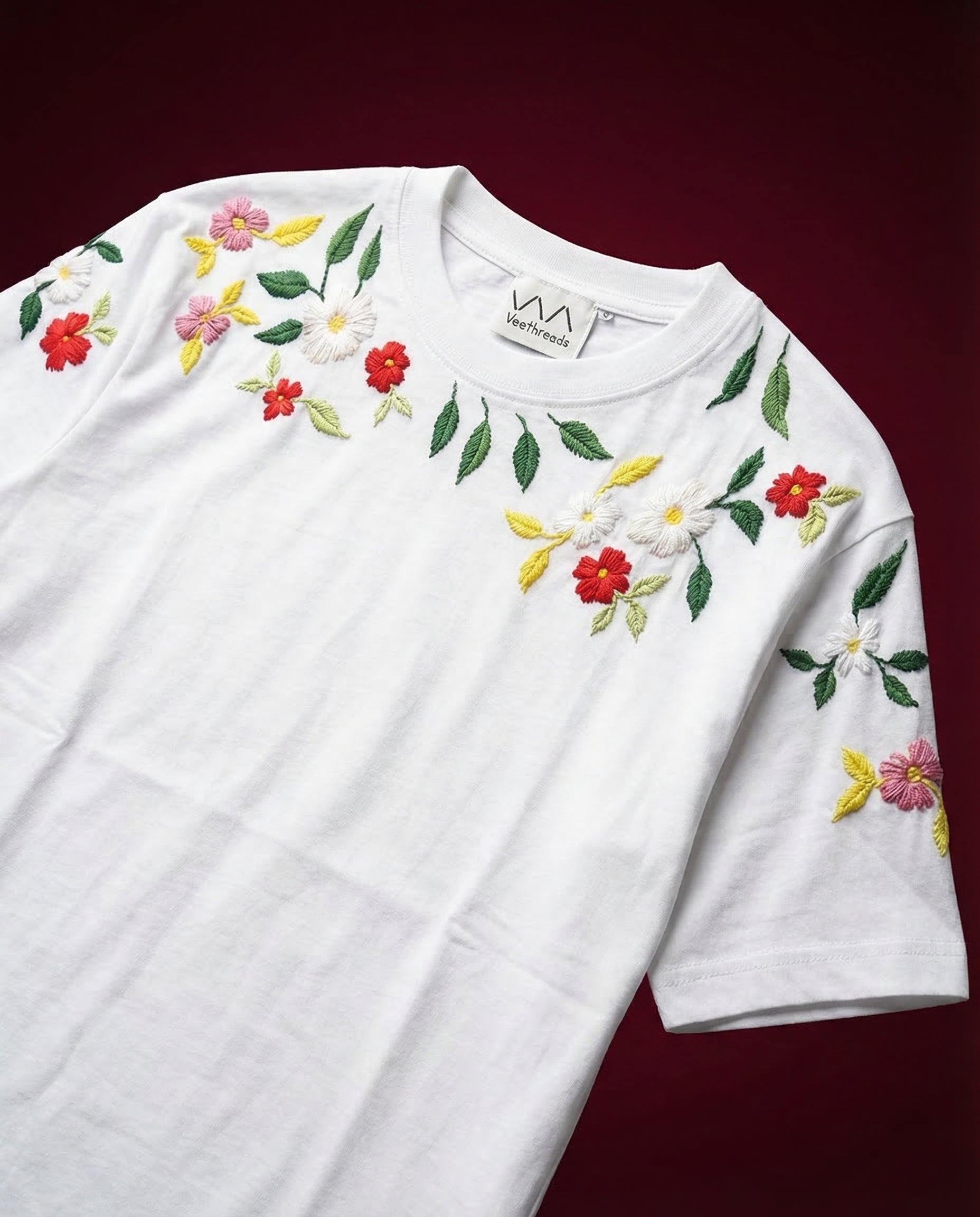 Close-up of hand embroidered daisy and floral shoulder detail on white Veethreads t-shirt