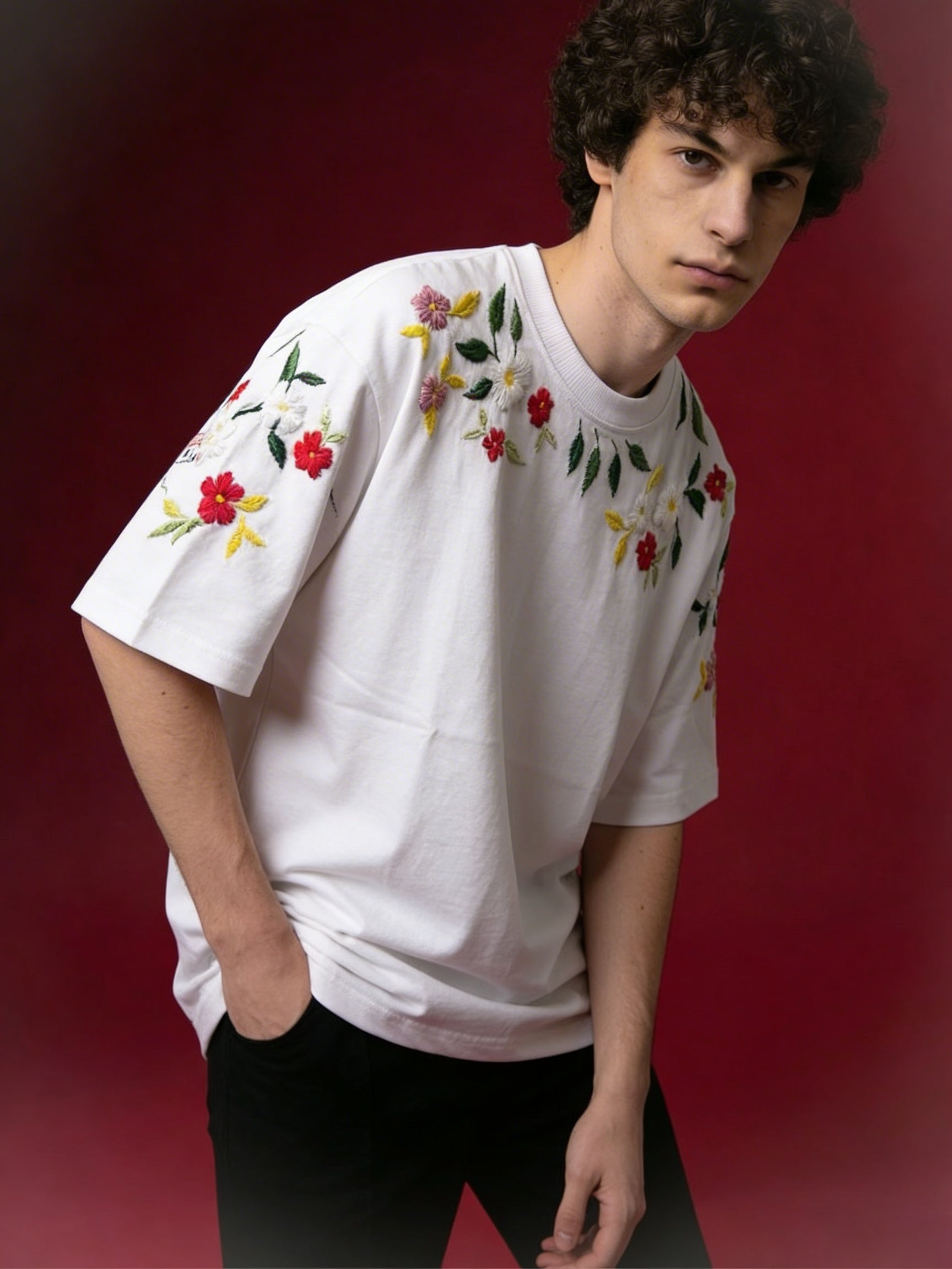 Person wearing a white t-shirt with floral embroidery on a red background