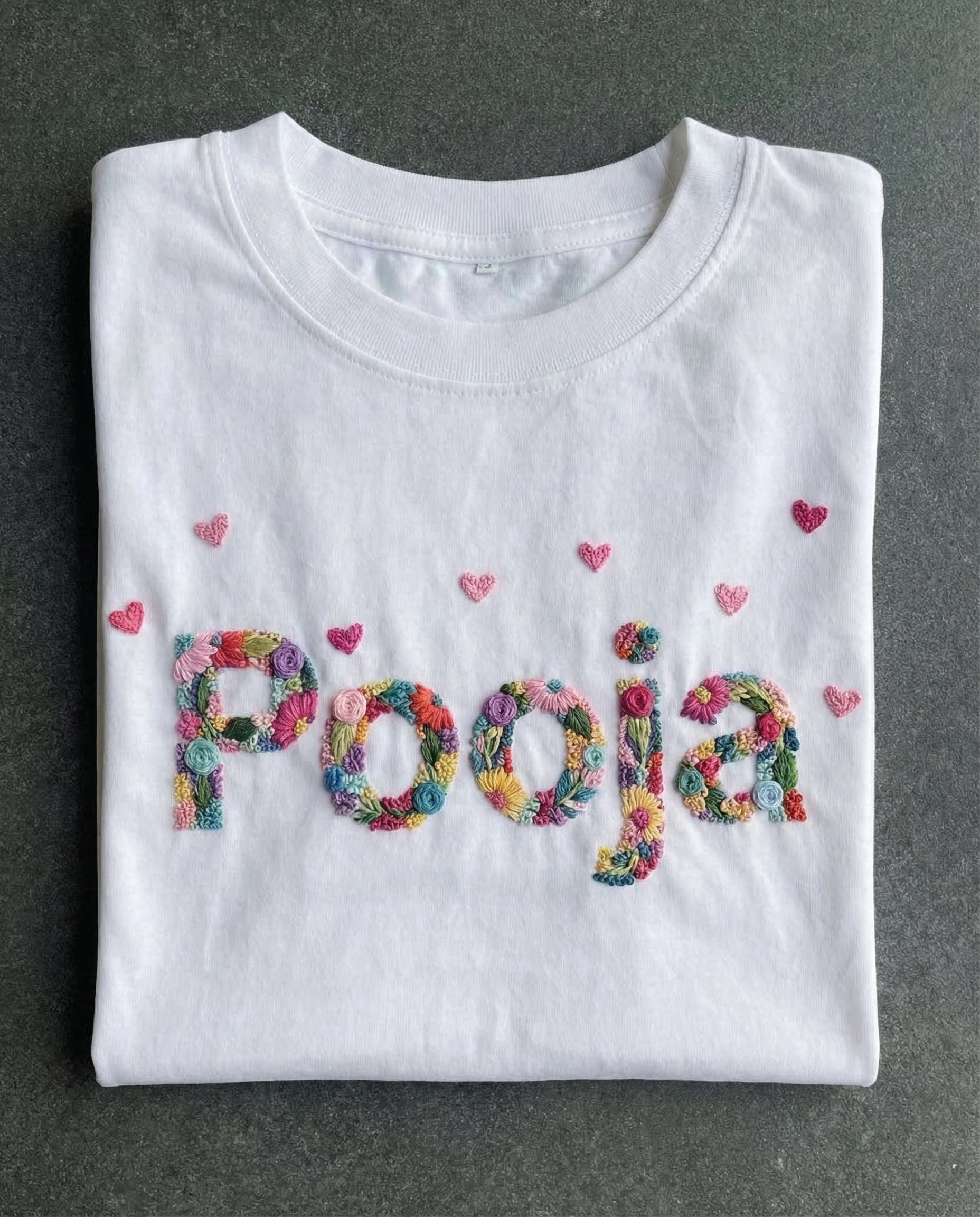 Name embroidery designs on shirt — white tee with 'Pooja' name hand-embroidered in colourful letters with hearts on dark background
