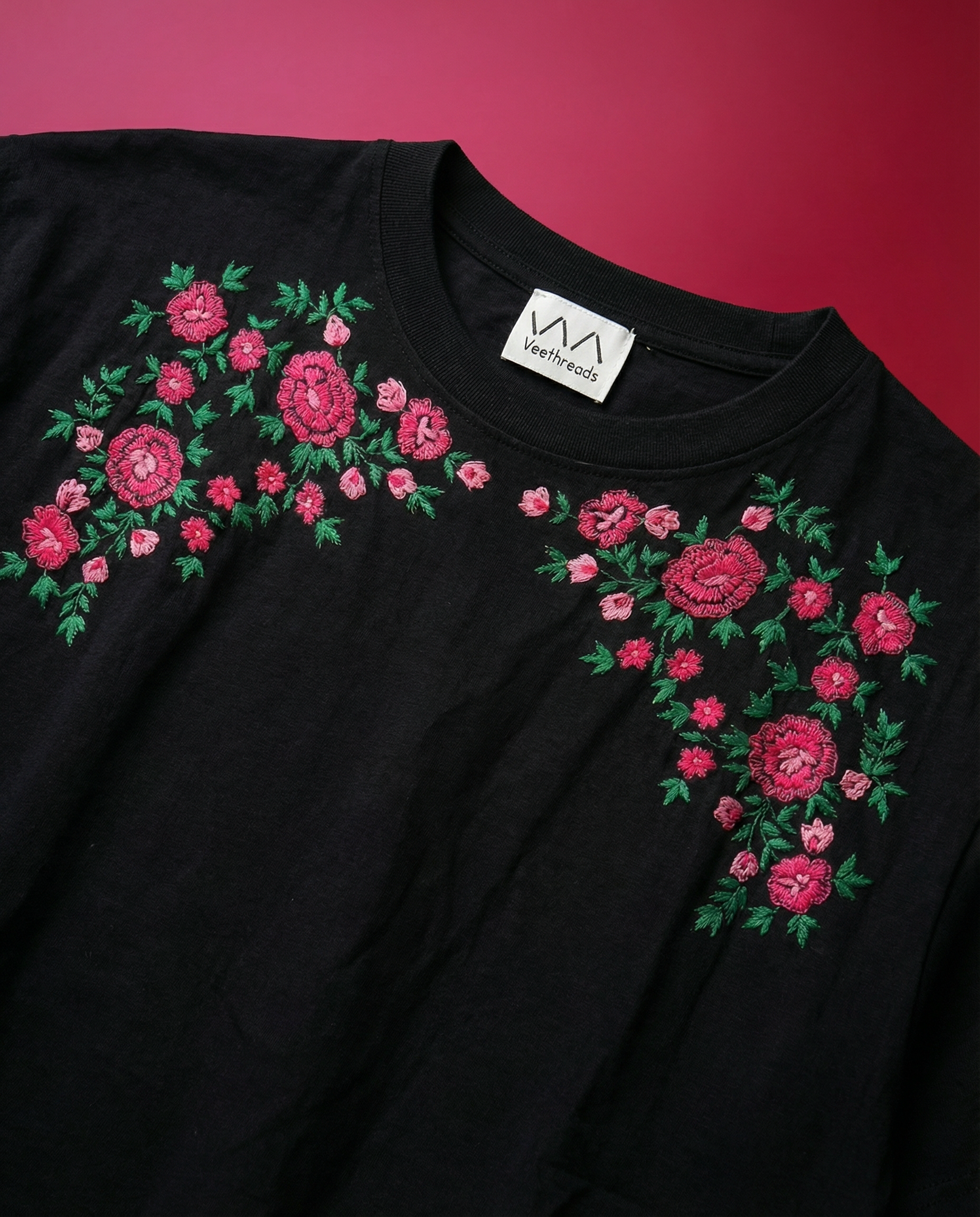 Black t-shirt with pink rose floral embroidery on a red background