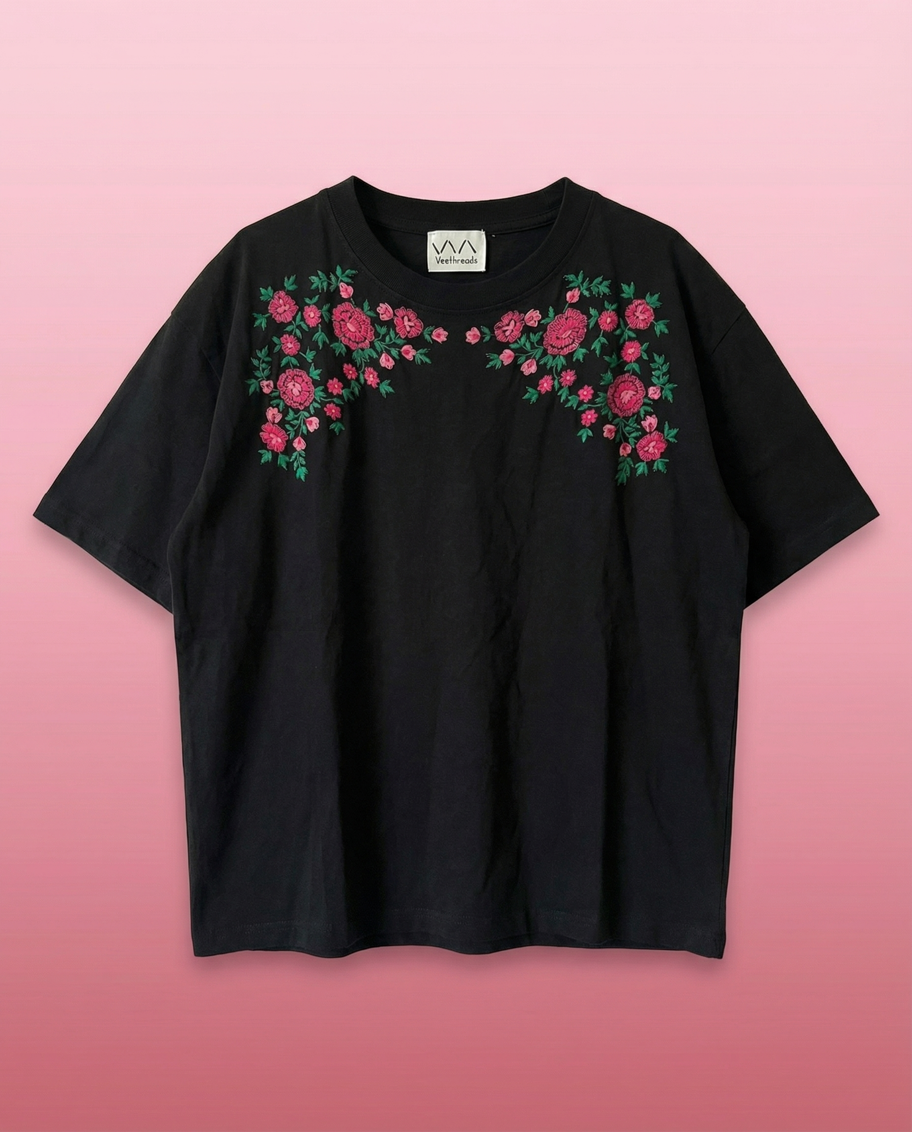 Black t-shirt with floral embroidery on a pink background