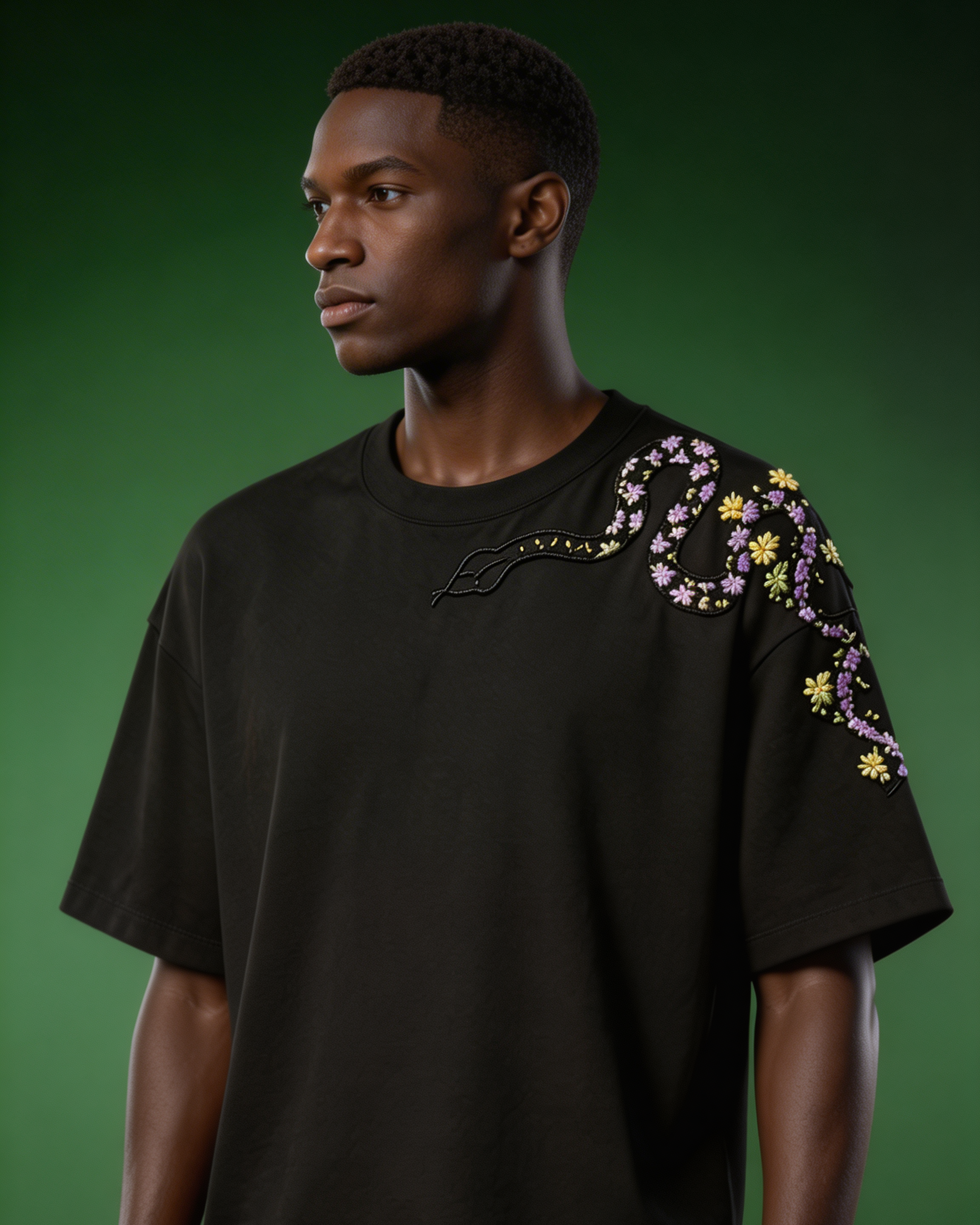 Man wearing a black t-shirt with floral embroidery on a green background