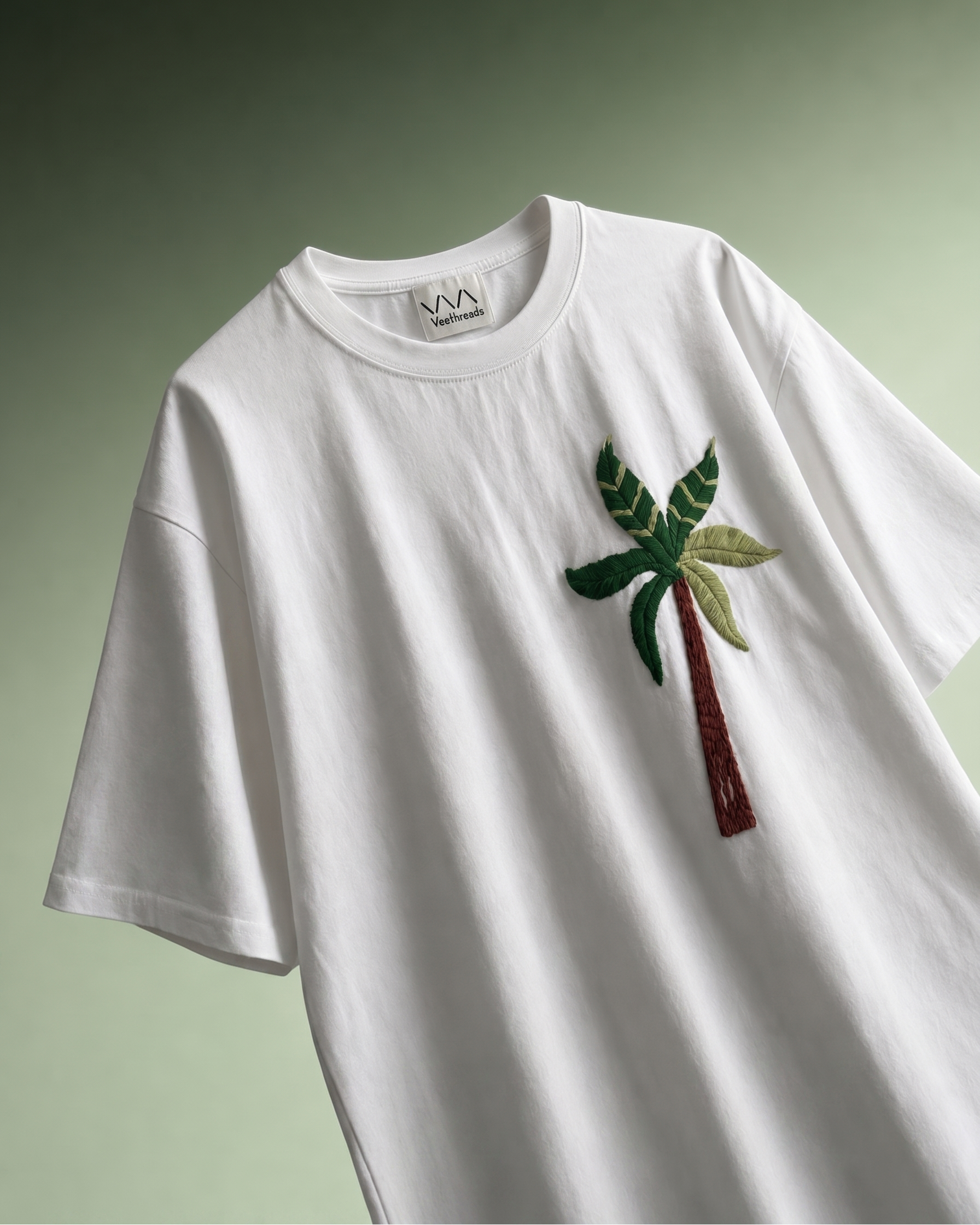 Palm tree embroidered t-shirt — white cotton tee with hand-embroidered coconut palm tree in six shades of green on light green background