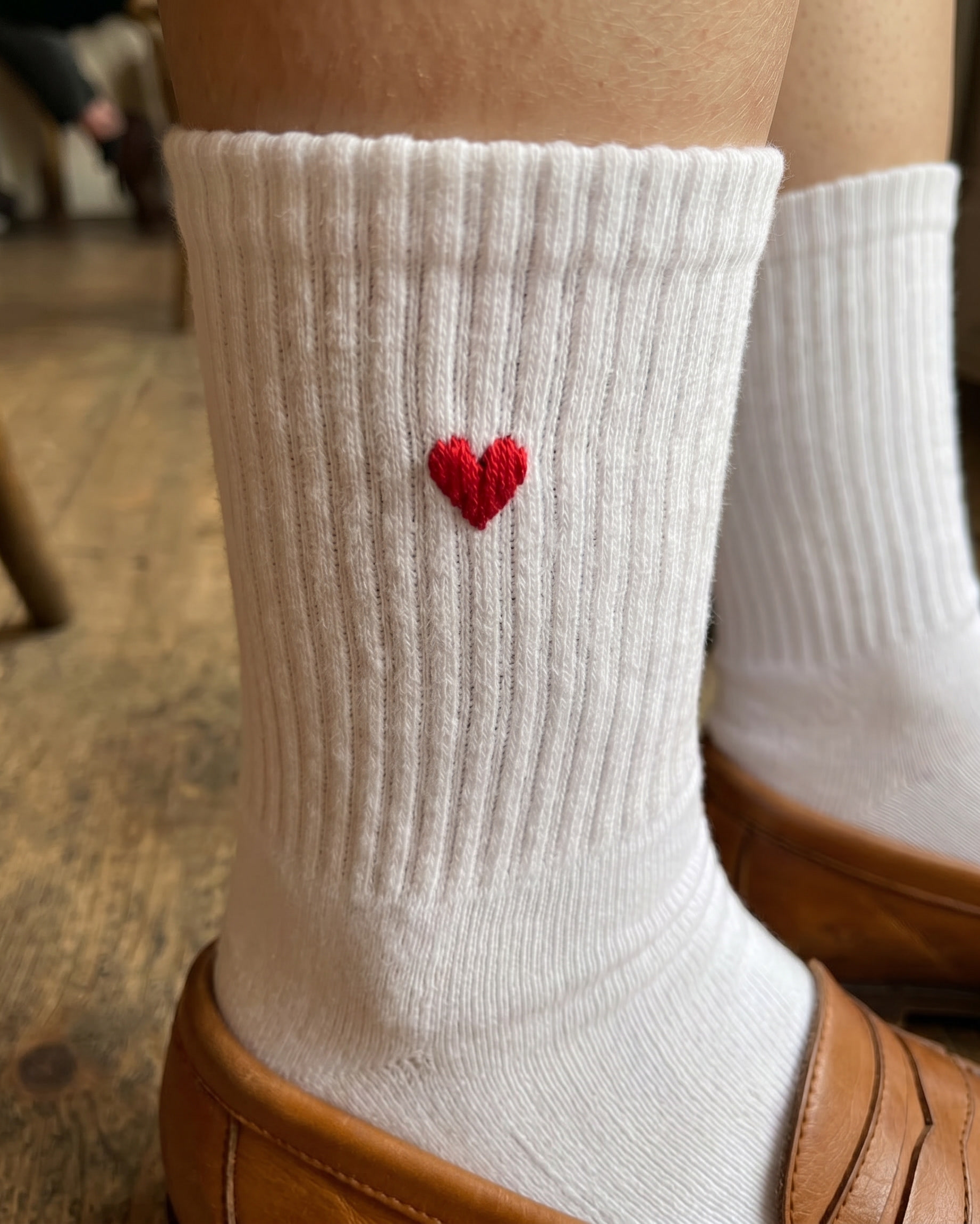 White sock with a red heart design worn indoors.