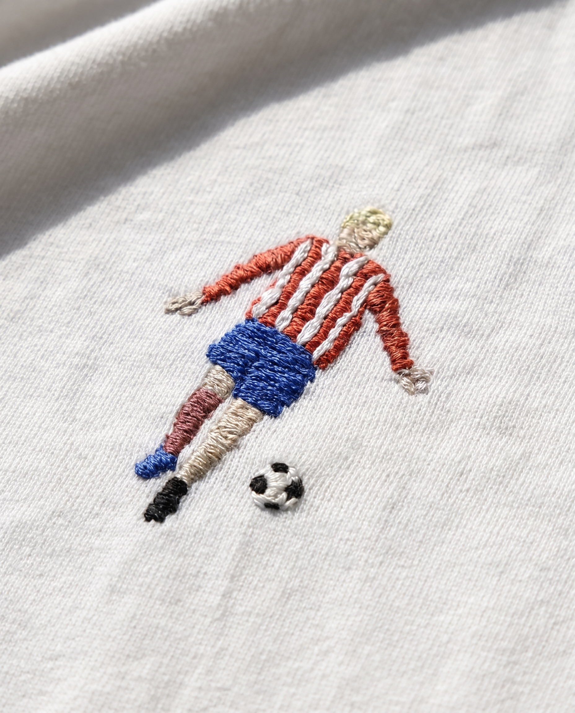 Hand-embroidered football players in coloured kits on a white cotton tee, by Vee Threads