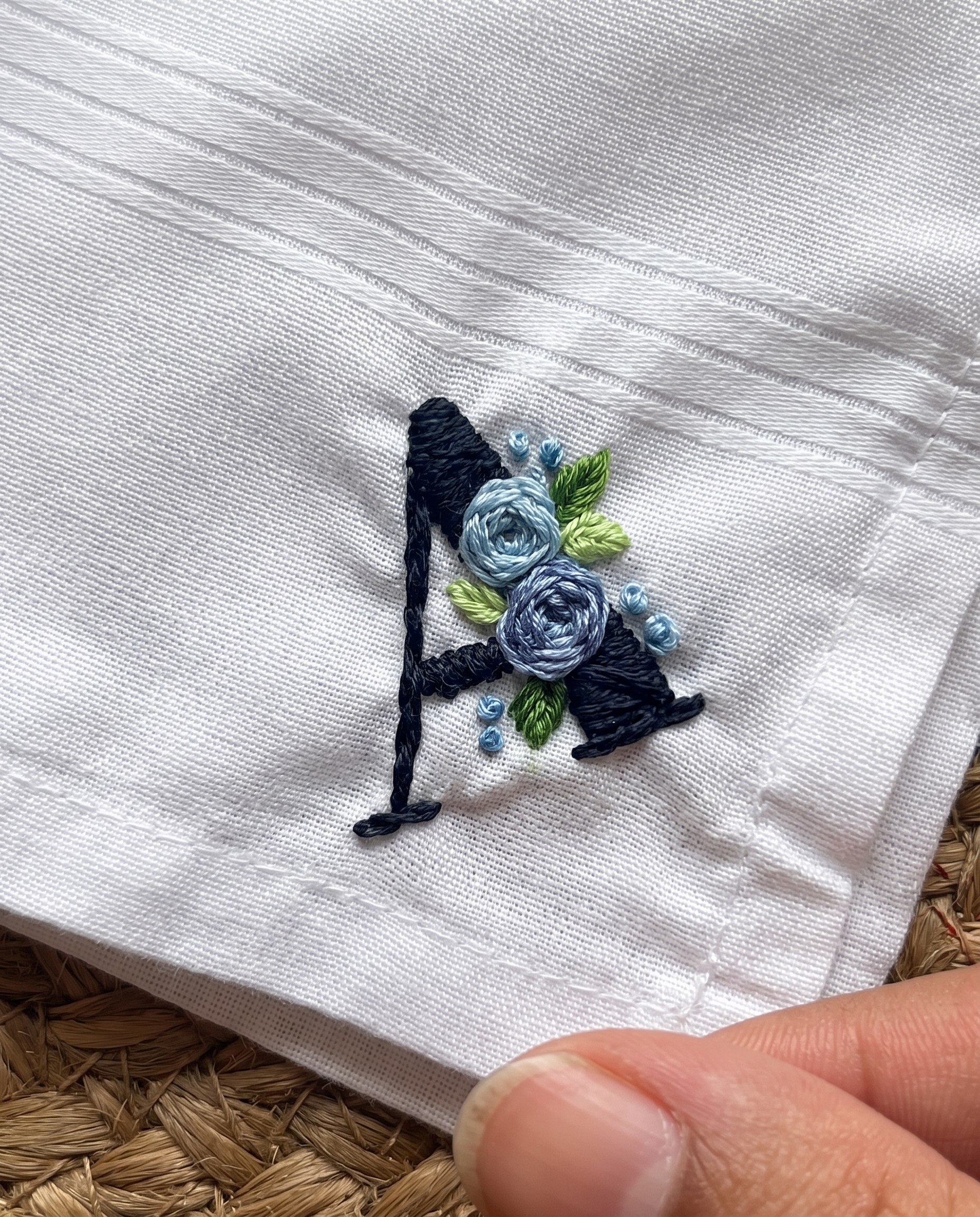 Hand embroidered handkerchief with a navy initial A and small blue flowers stitched on white cotton