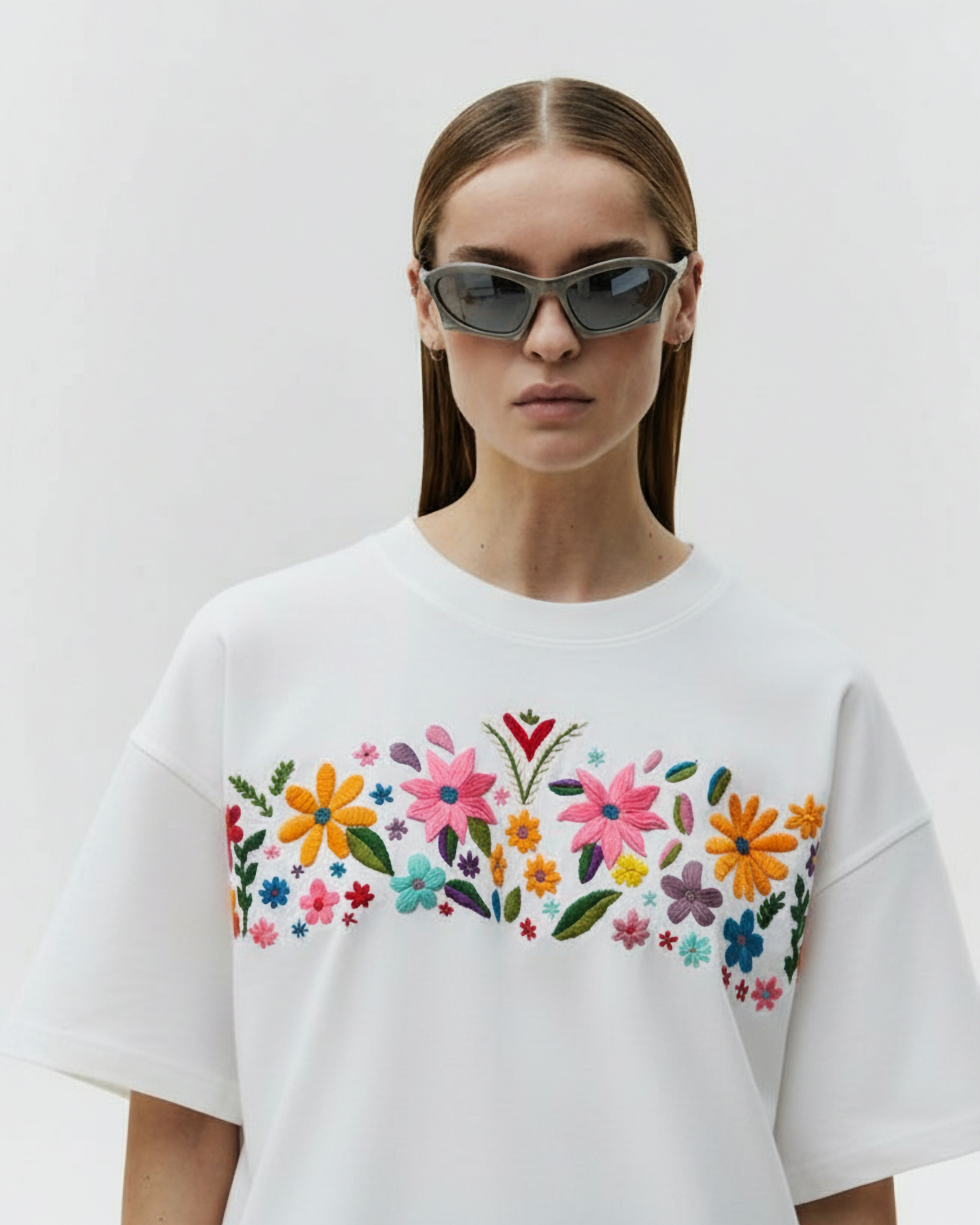 Person wearing a white t-shirt with colorful floral design on a plain background