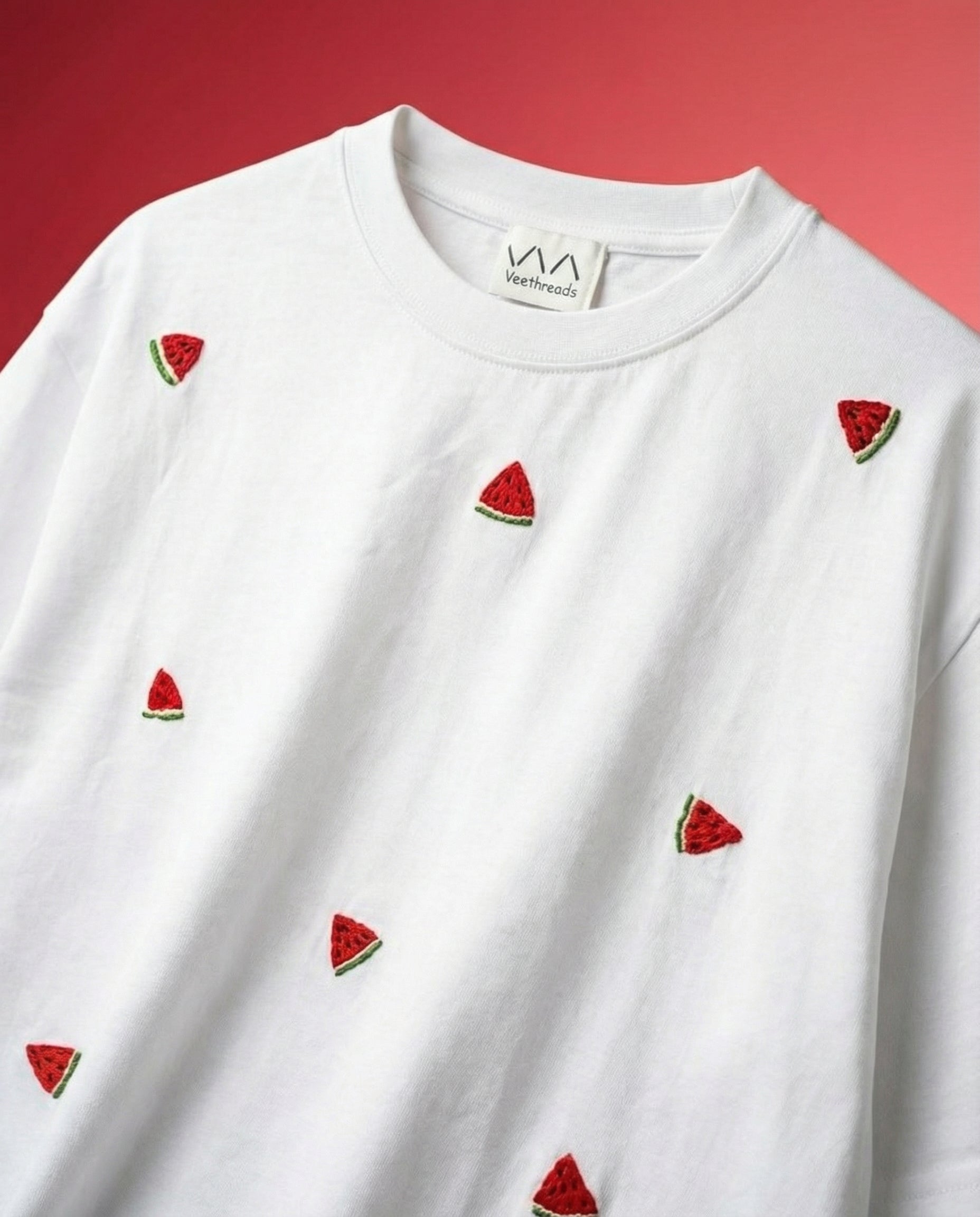 White cotton tee with a hand-embroidered watermelon slice on a red background