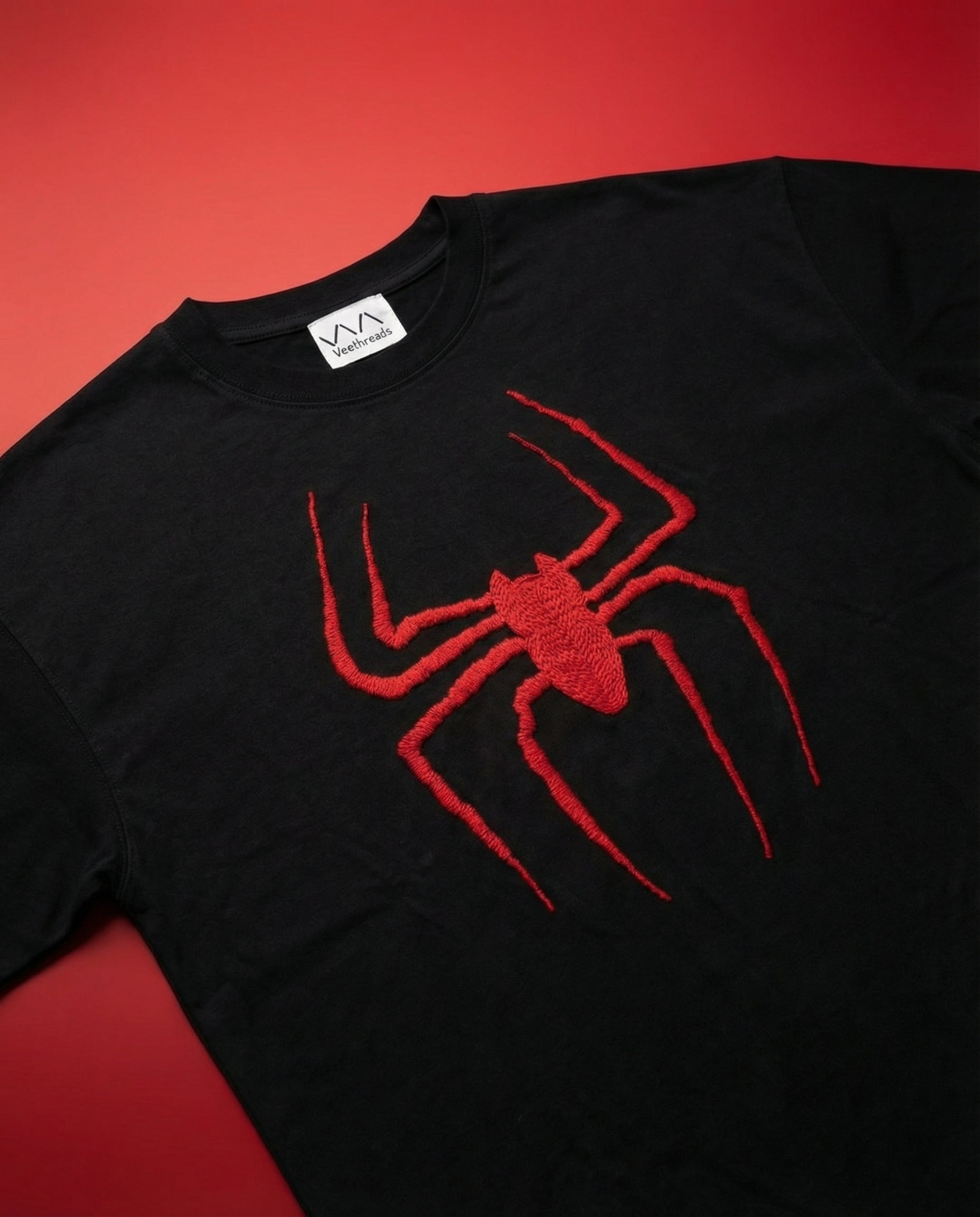 Close up of a spider web hand-embroidered in real thread on an oversized cotton t-shirt