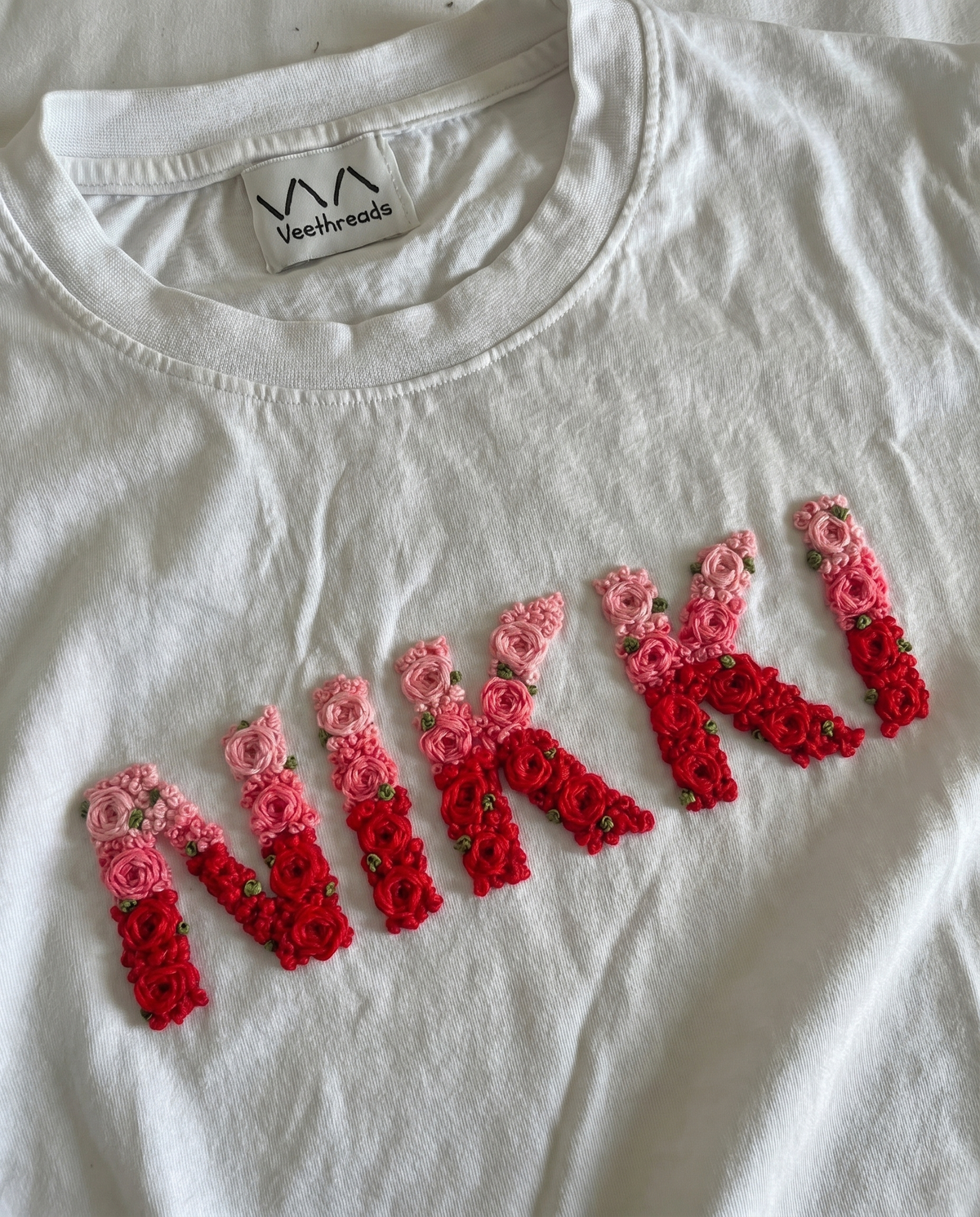 Name embroidery design hand-stitched in double-shade thread on a white cotton oversized tee