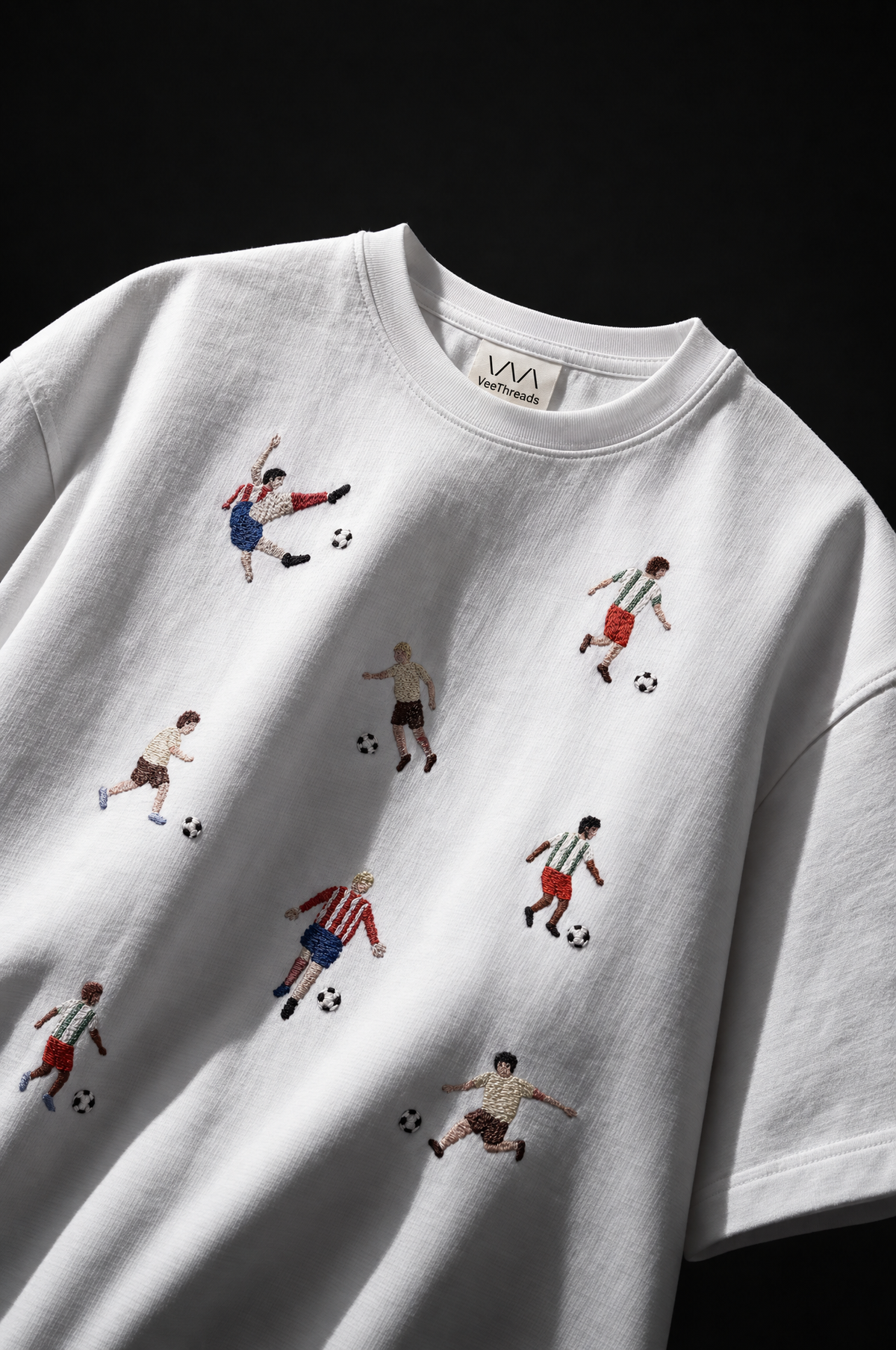Little footballers and soccer balls hand-embroidered across a white t-shirt
