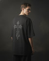 Person wearing a black t-shirt with a white graphic design on the back against a dark background