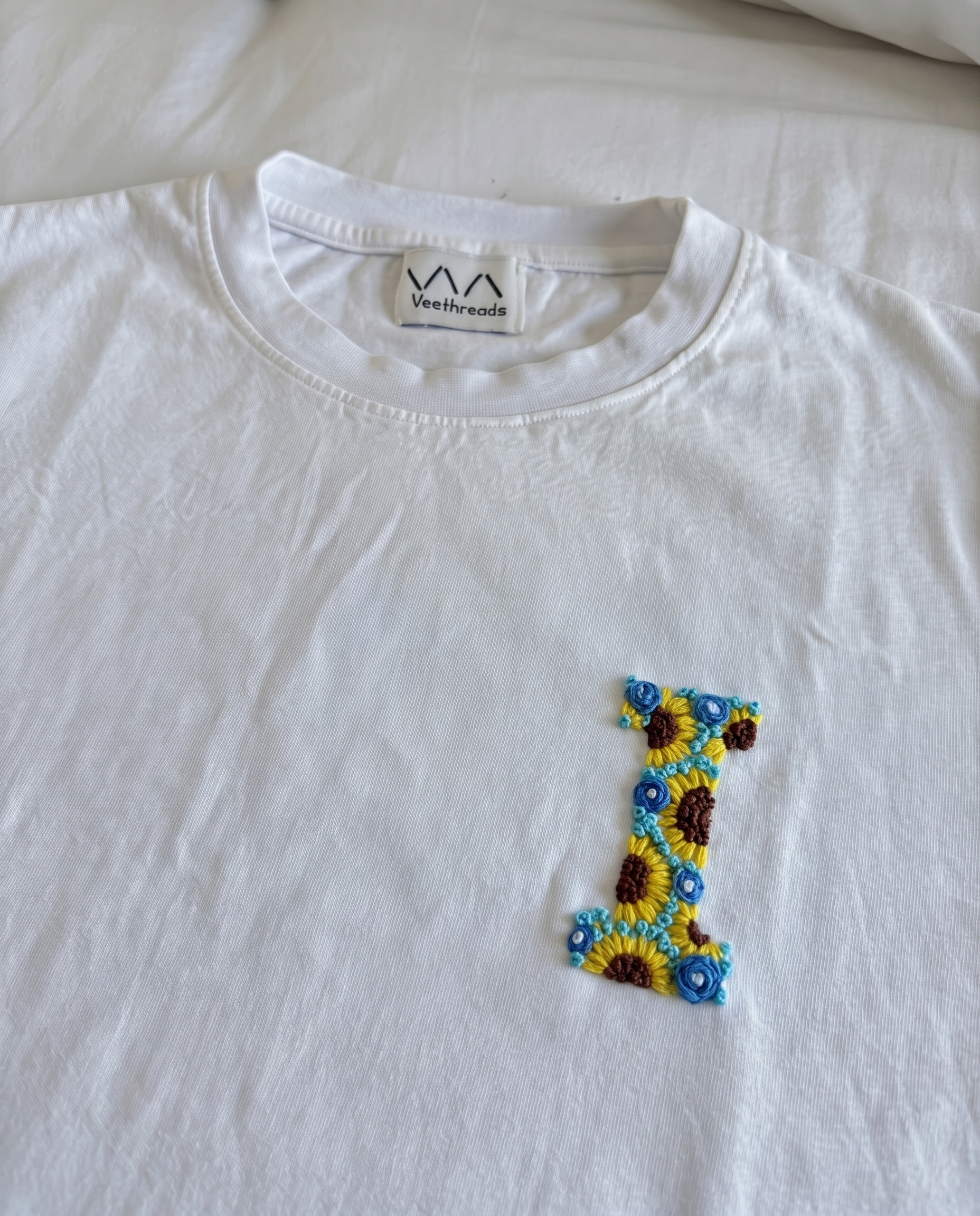 Custom initial stitched from sunflowers and small blue flowers on white cotton, by Vee Threads
