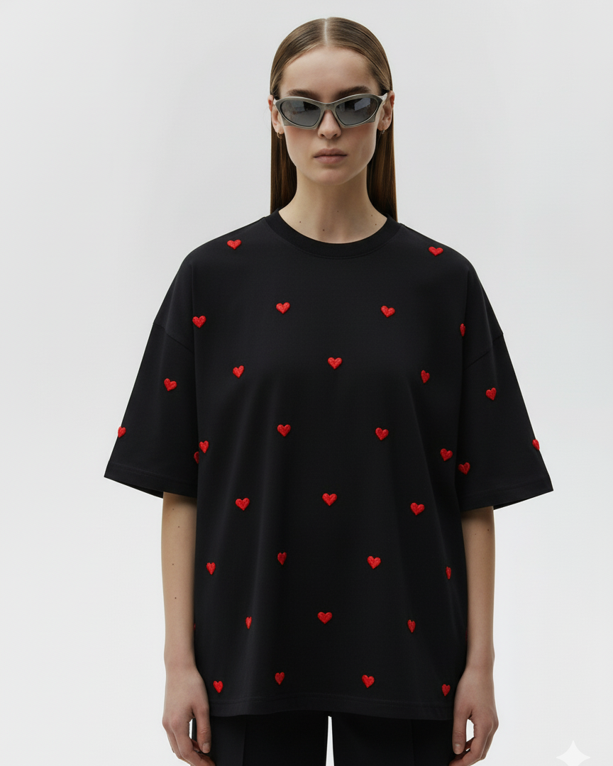 Person wearing a black t-shirt with red heart patterns hand embroidered  on a white background