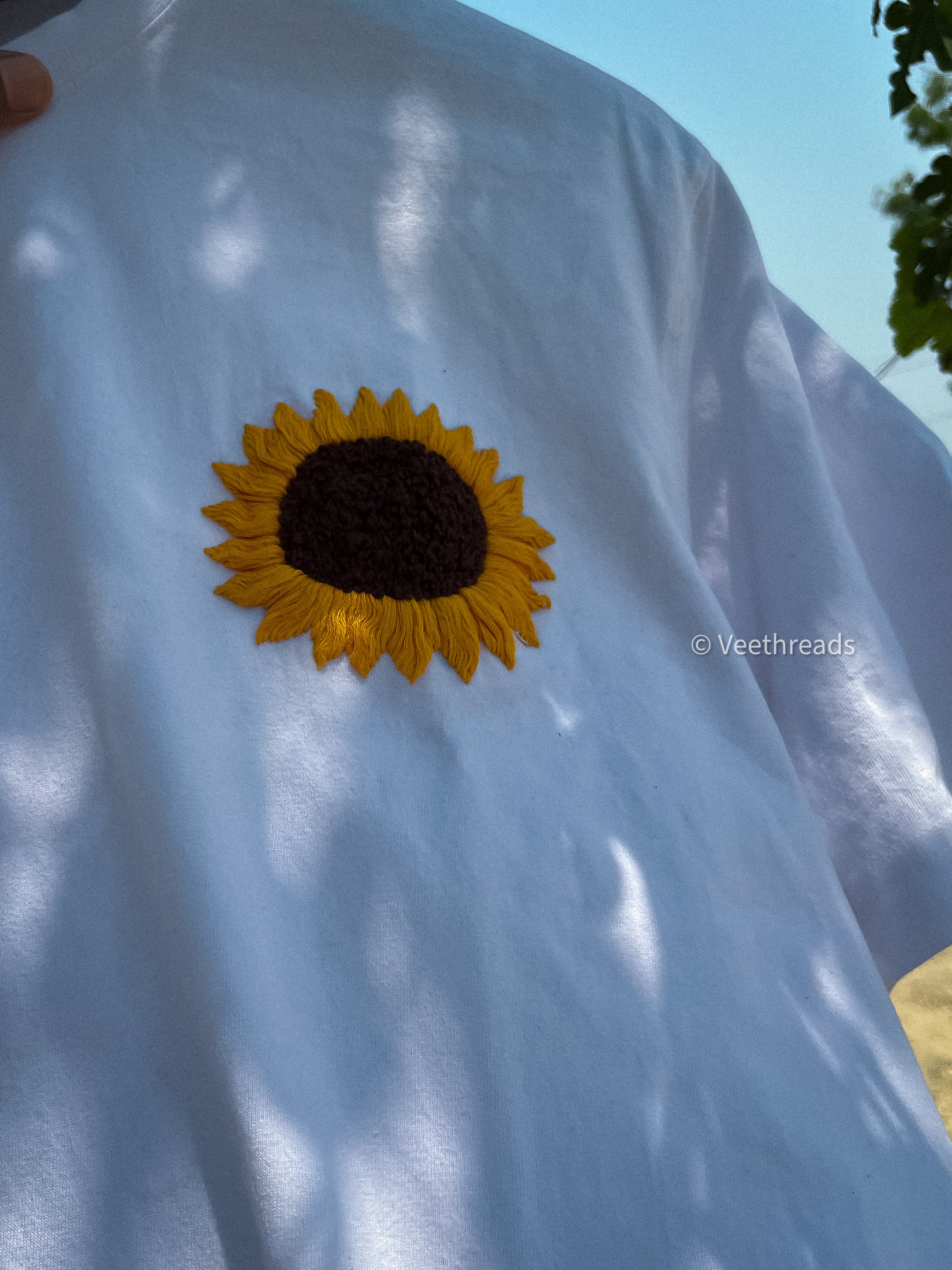 Elegant sunflower hand embroidery on a comfortable sweatshirt, blending warmth and style with artisanal craftsmanship.