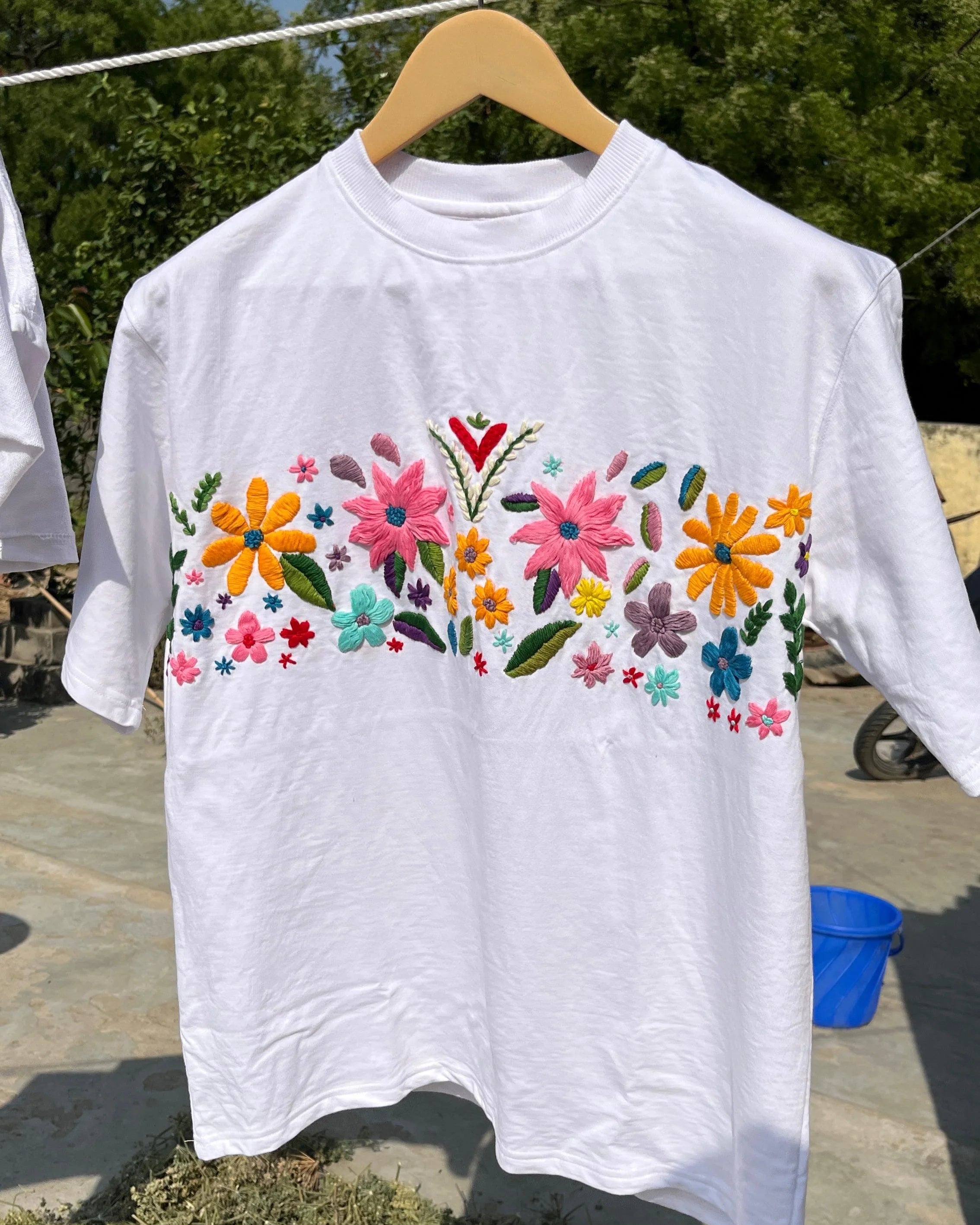 Flat lay of black cotton t-shirt with vibrant floral hand embroidery