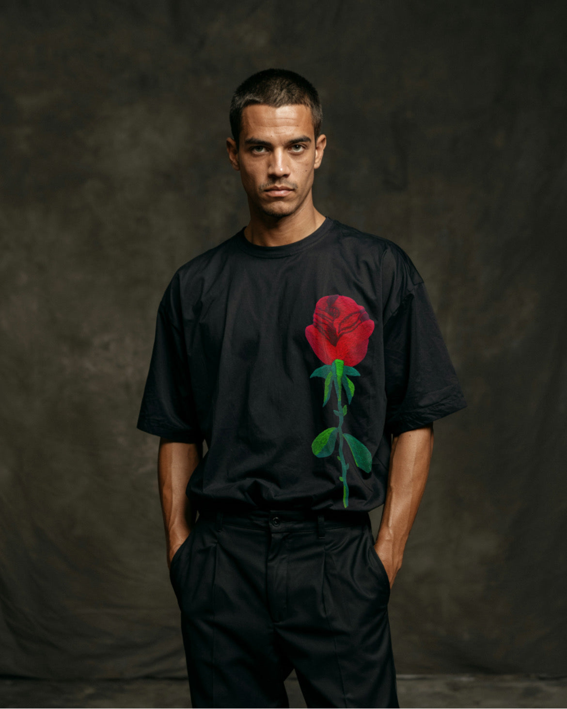 Oversized rose embroidered tee styled with skirt and boots, worn by  model in natural lighting.