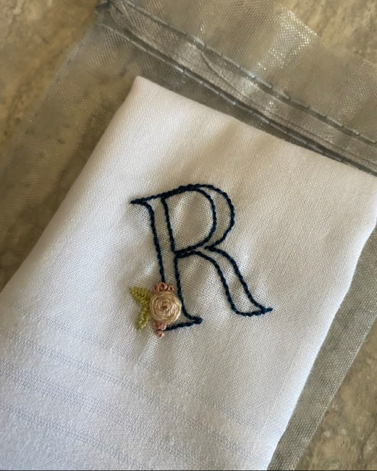 Monogrammed handkerchief with a navy embroidered letter R and a small rose on white cotton