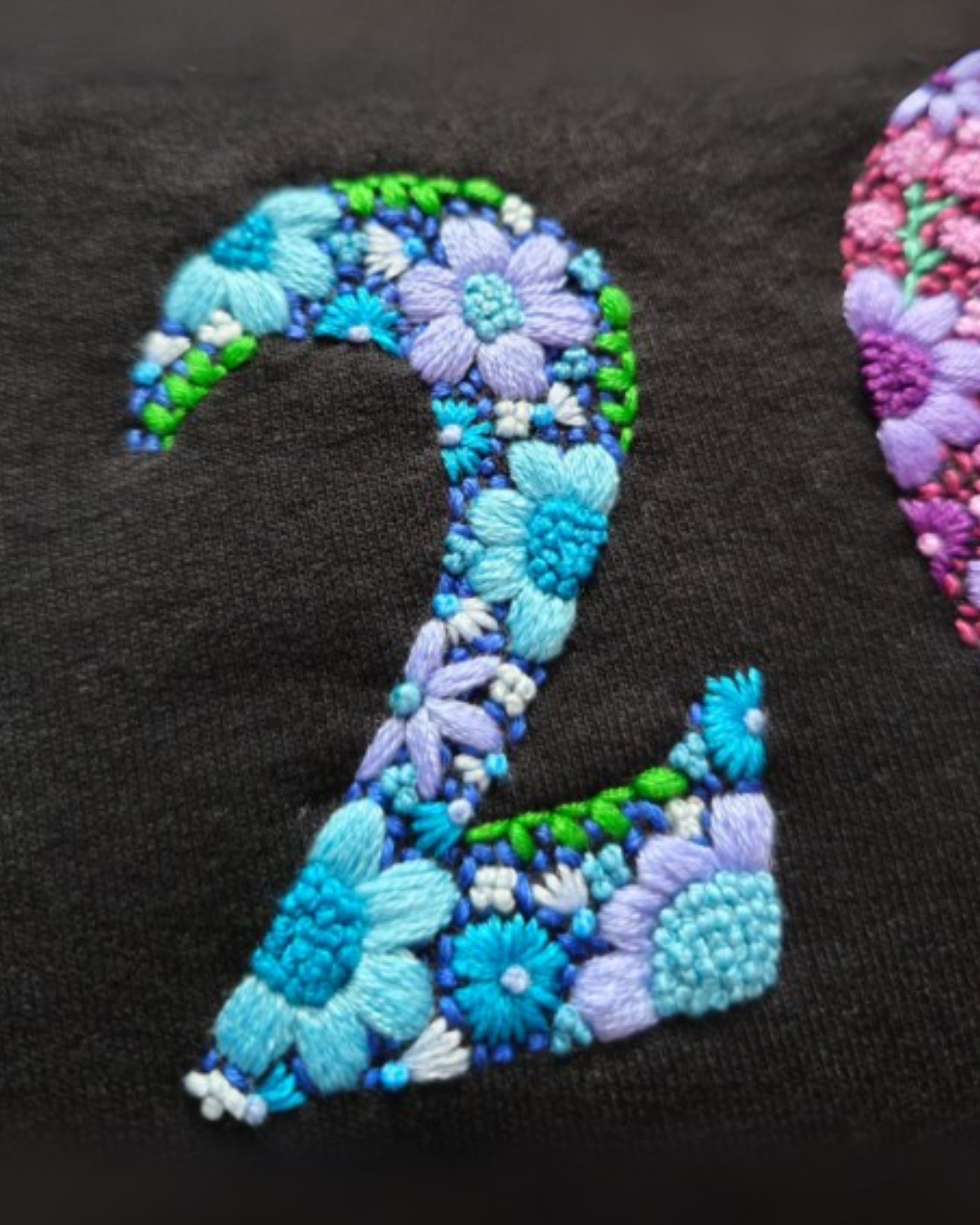Floral embroidered number '2' on a black background