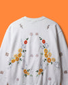 White sweatshirt with floral embroidery on an orange background