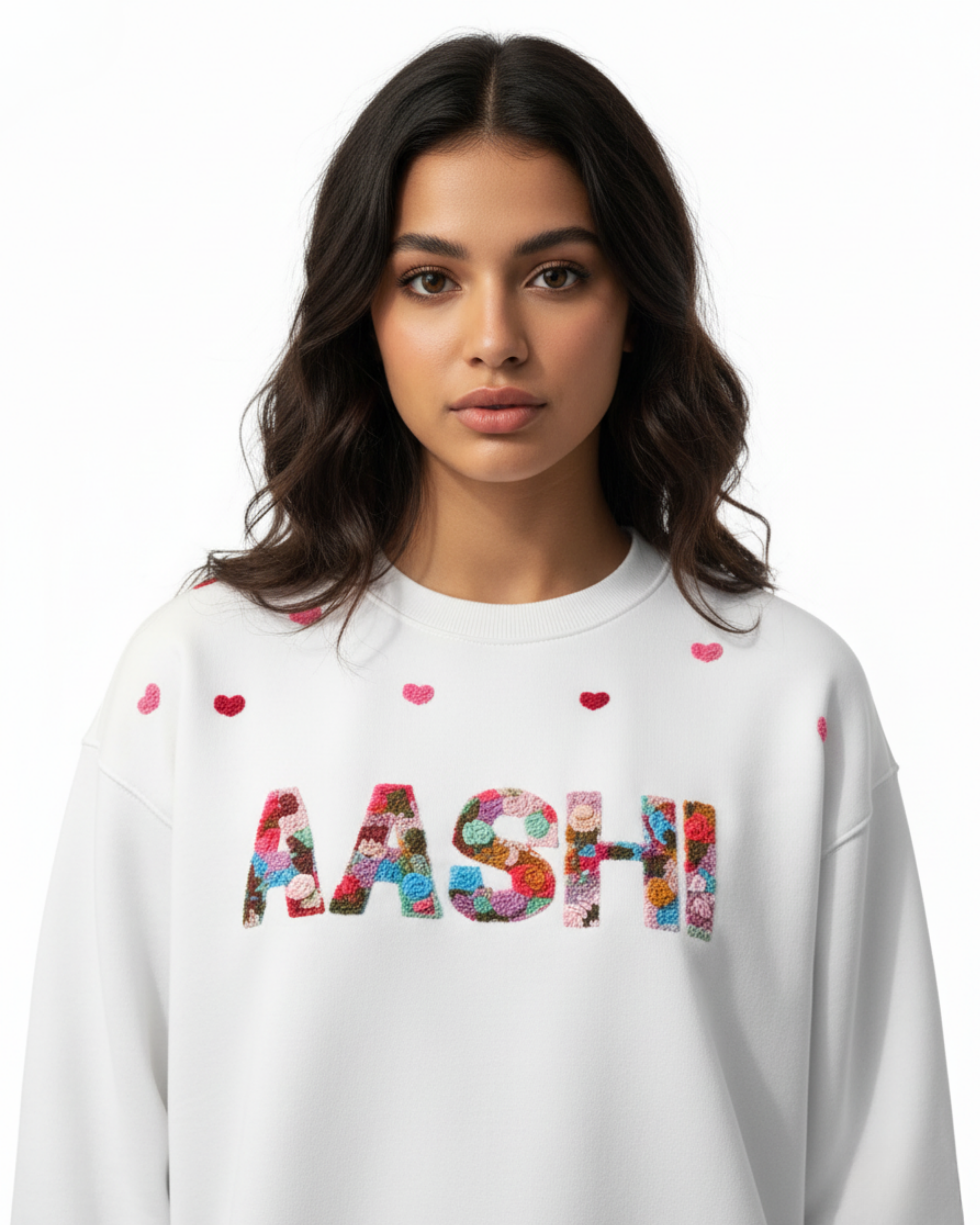 Woman wearing a white sweatshirt with colorful letters spelling 'MASHI' custom name hand embroidered  on a plain background